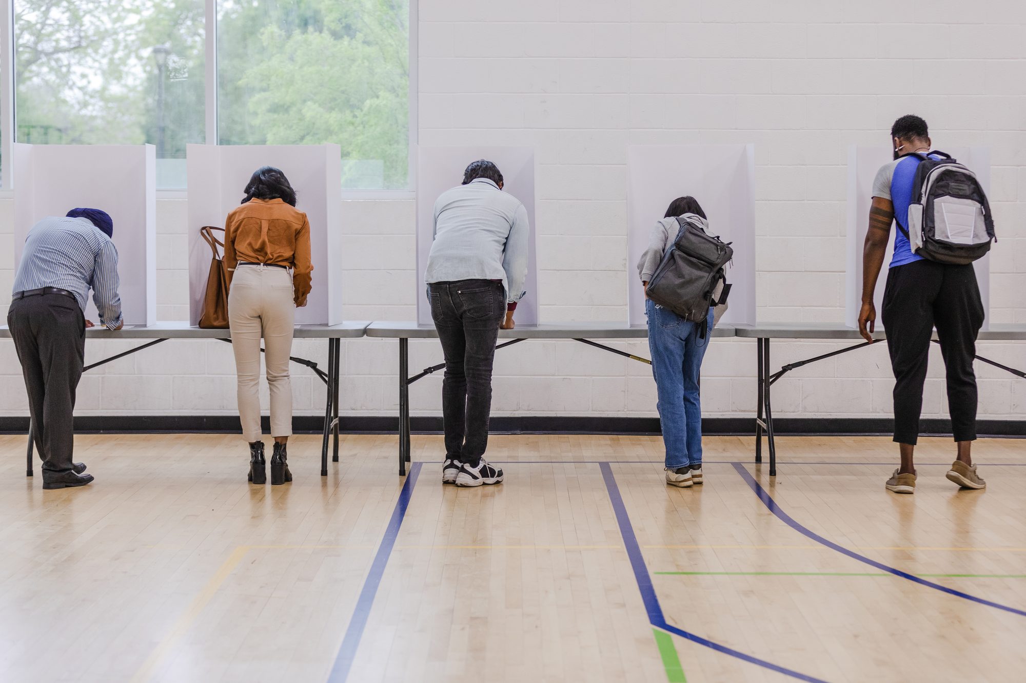 Rear view of multiracial voters completing their ballots for the election