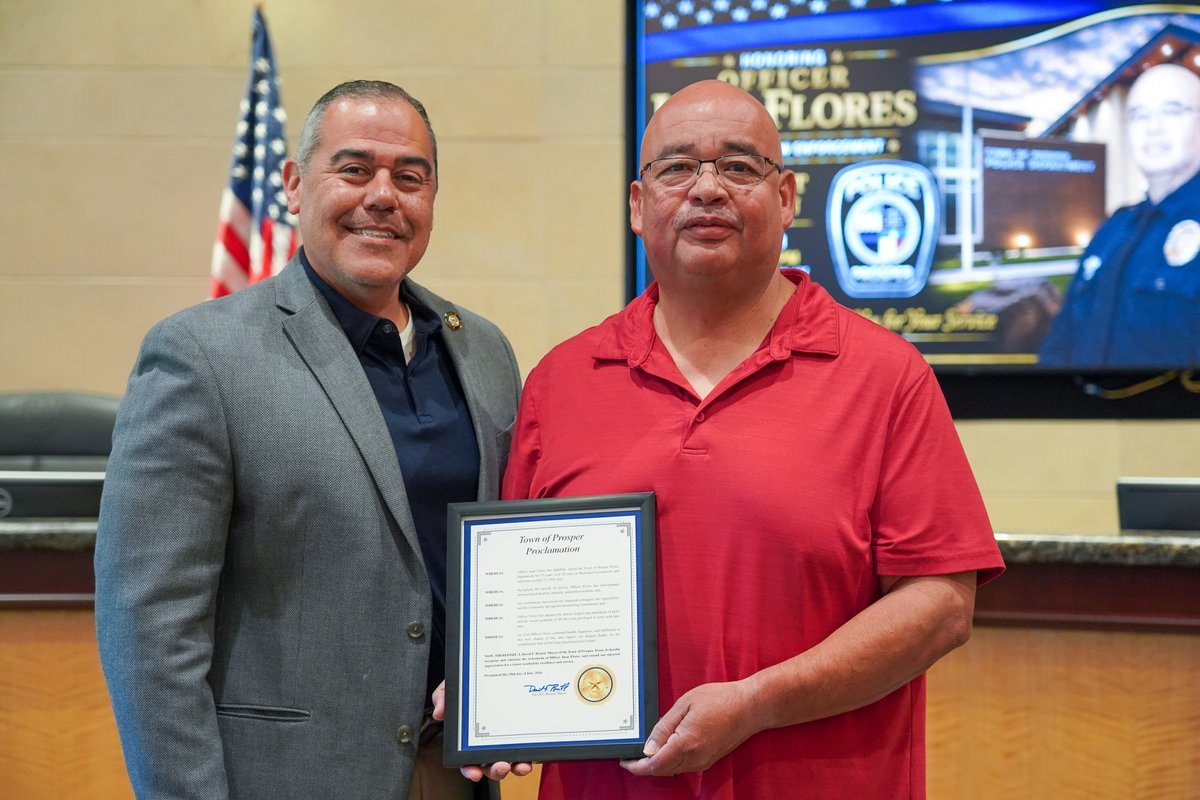 Two men pose with a framed certificate; a screen behind them reads 'Honoring Officer Flores.'