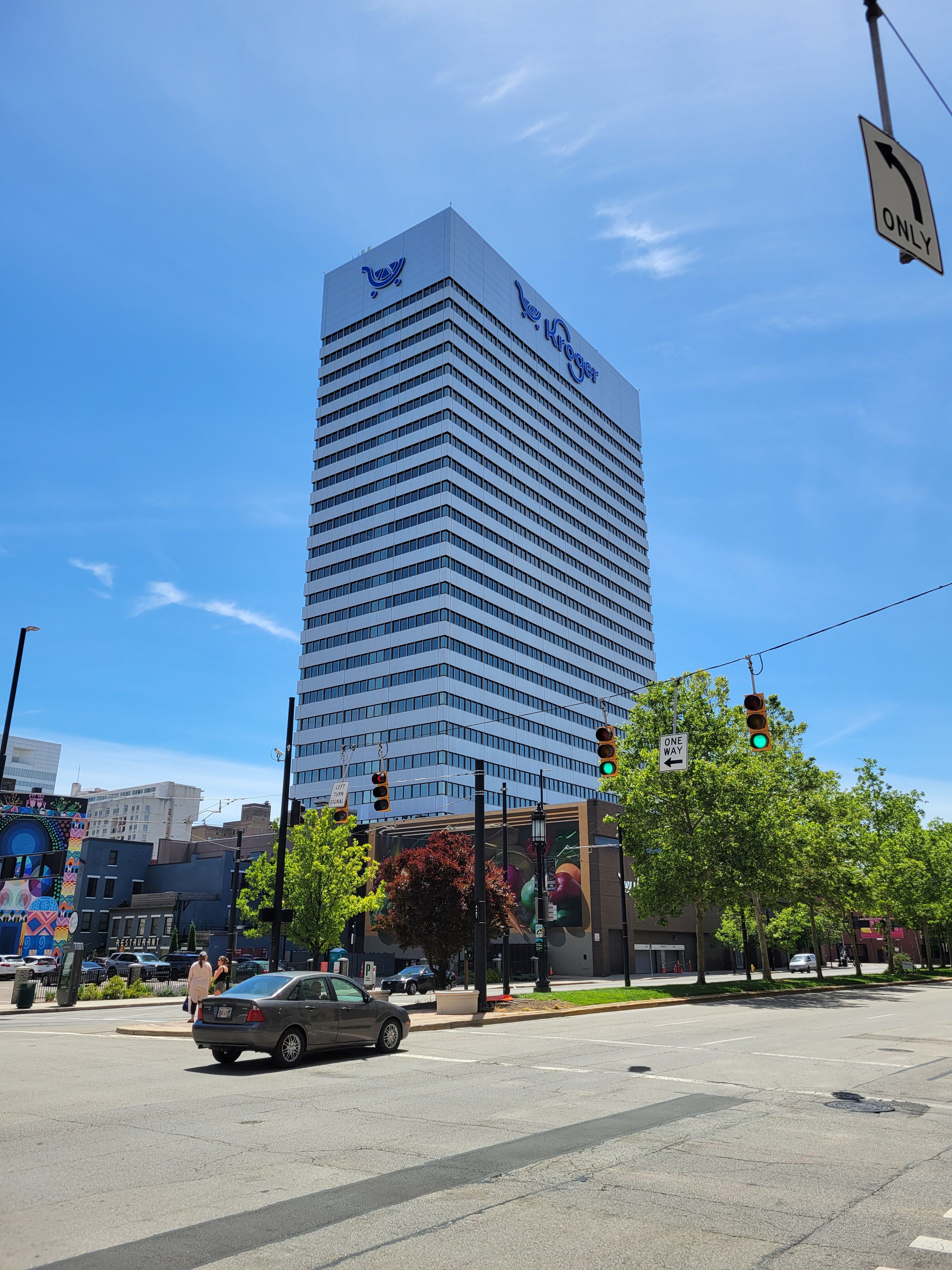 Tall white office tower with Kroger signage, viewed from a downtown street intersection.