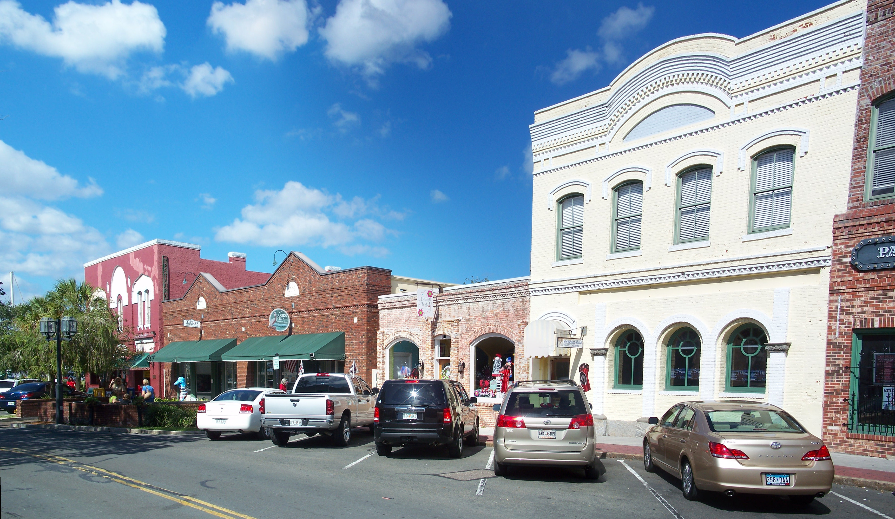 Panoramic view of a historic downtown street lined with two-story commercial buildings and parked cars.