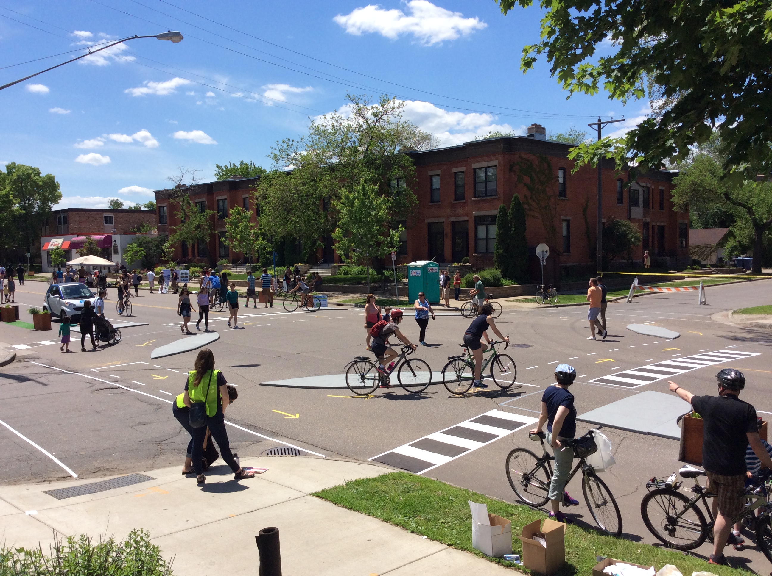 Cyclists and pedestrians move through a protected bike lane intersection with temporary lane markings.