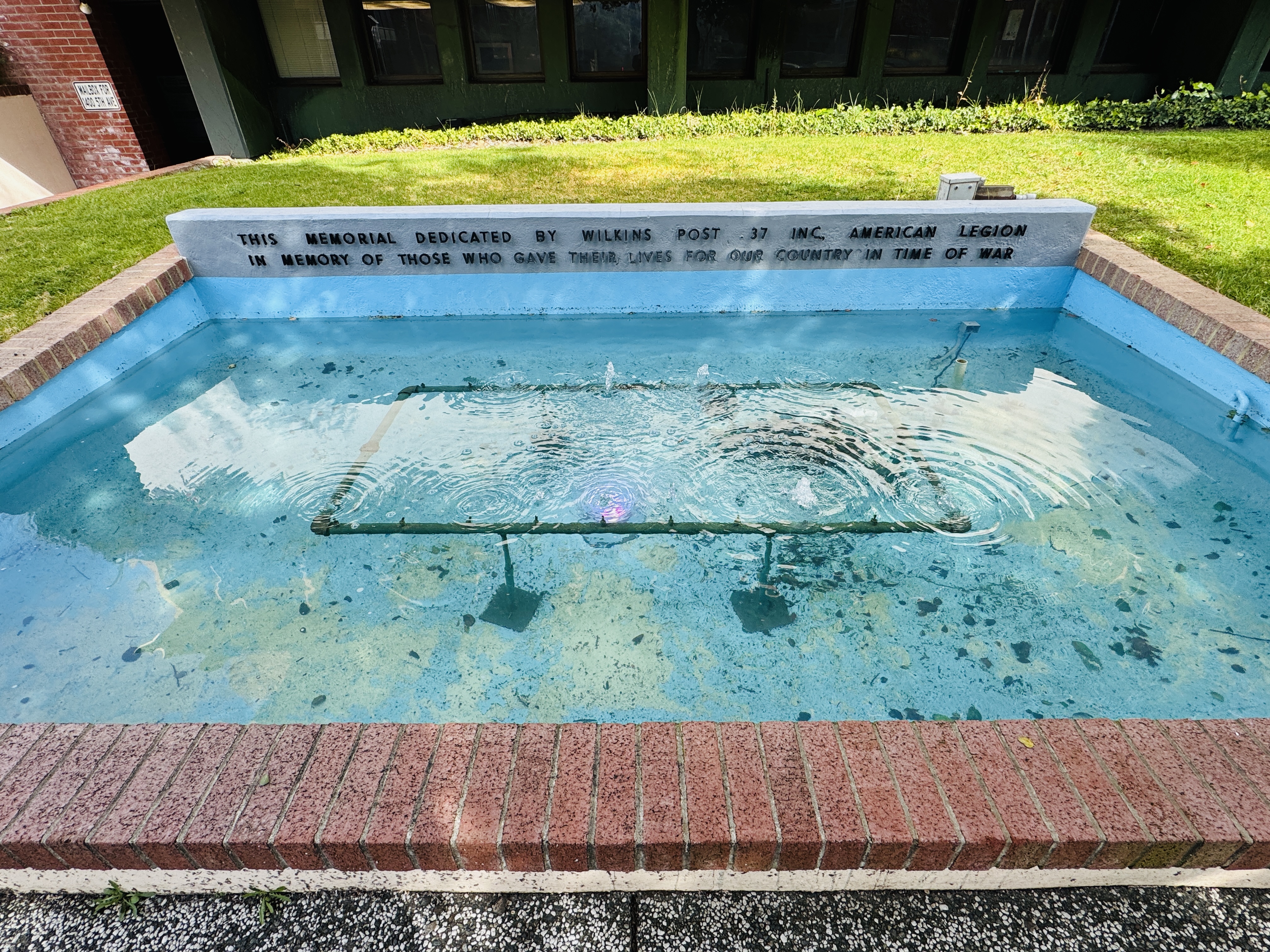 Outdoor reflecting pool memorial with brick edging at San Rafael City Hall.