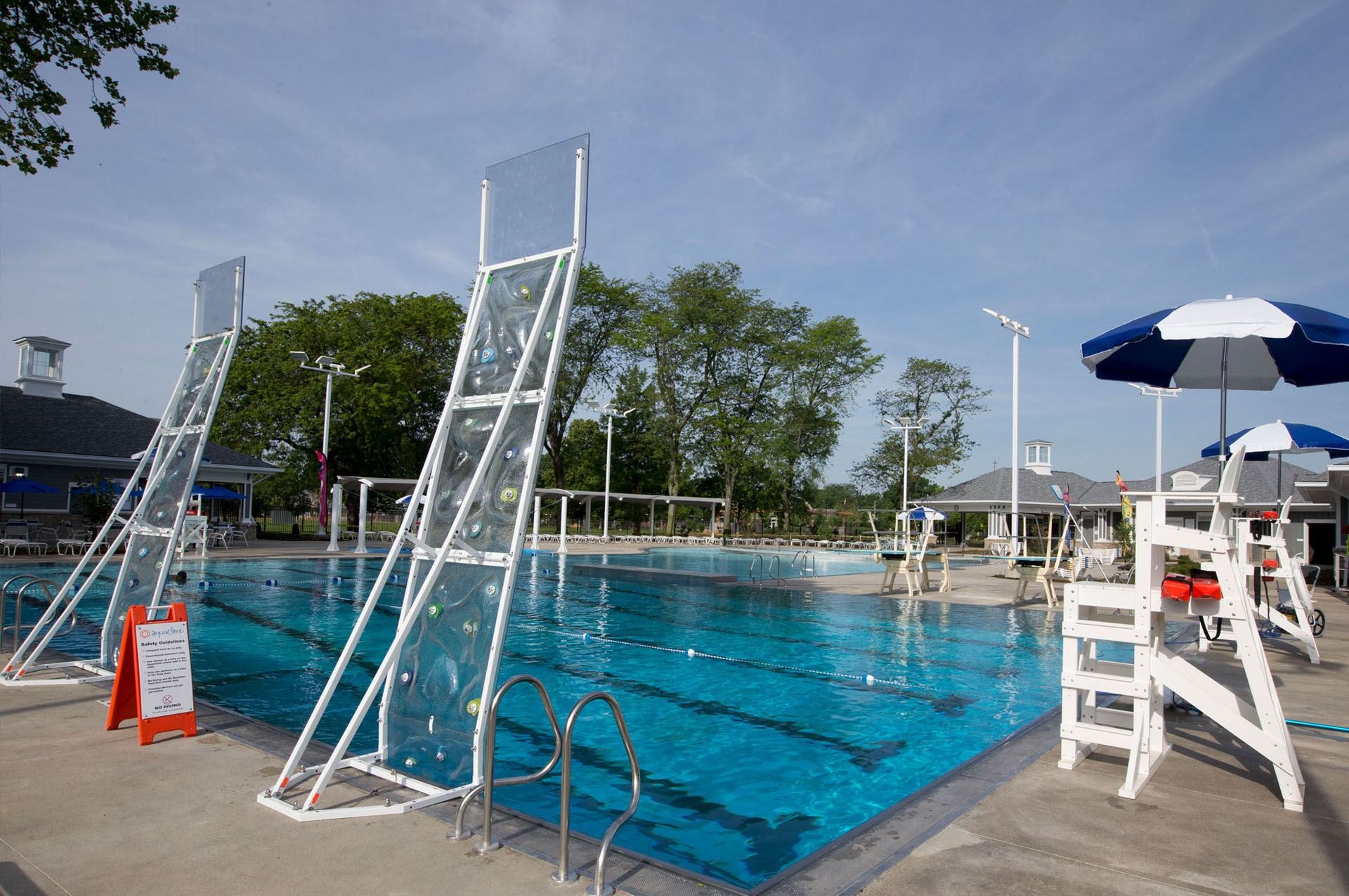 Outdoor public swimming pool with blue water, lane dividers, and a lifeguard stand on a sunny day.