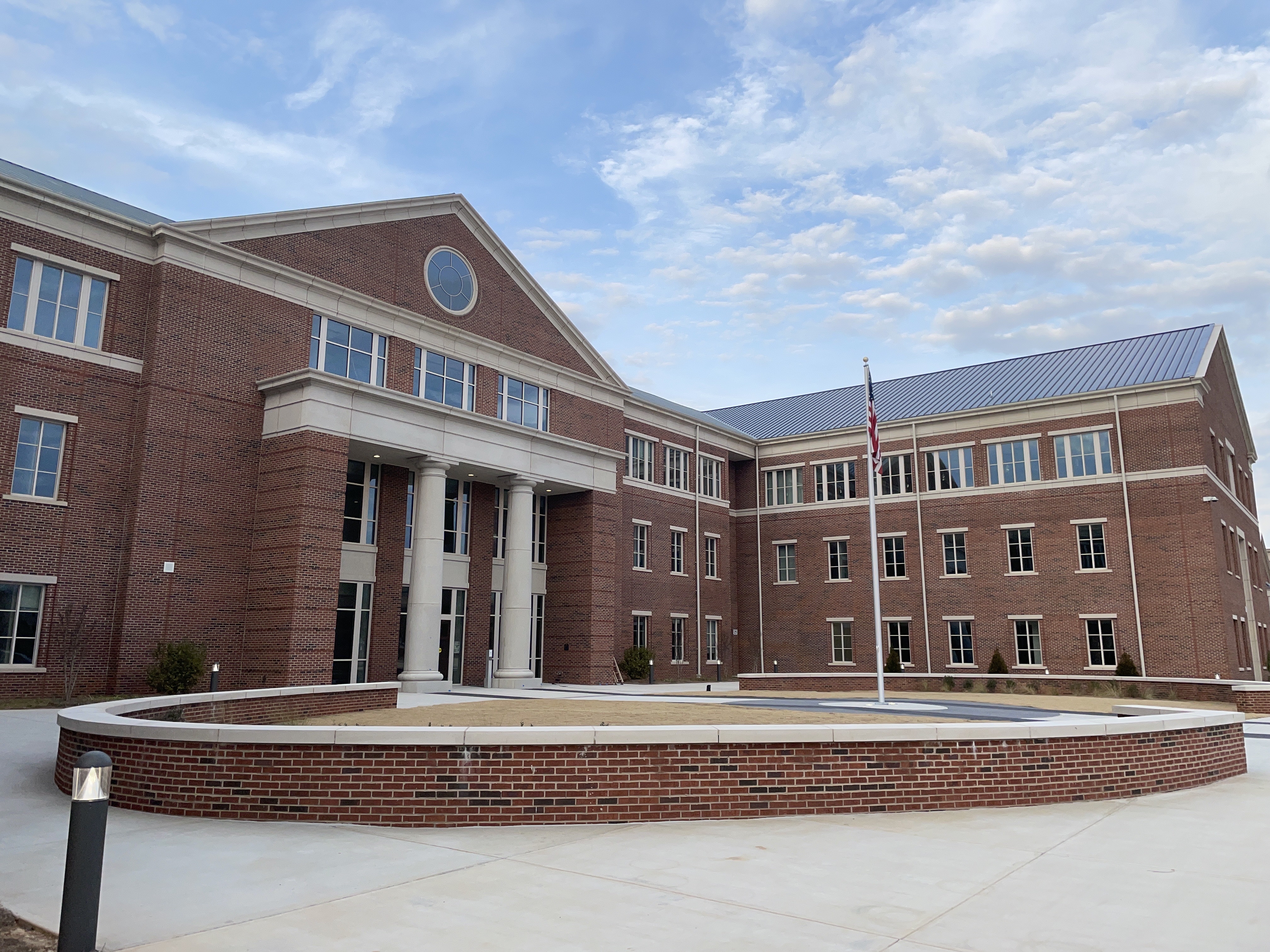 Multi-story red-brick school building with columned entrance and American flag on flagpole.