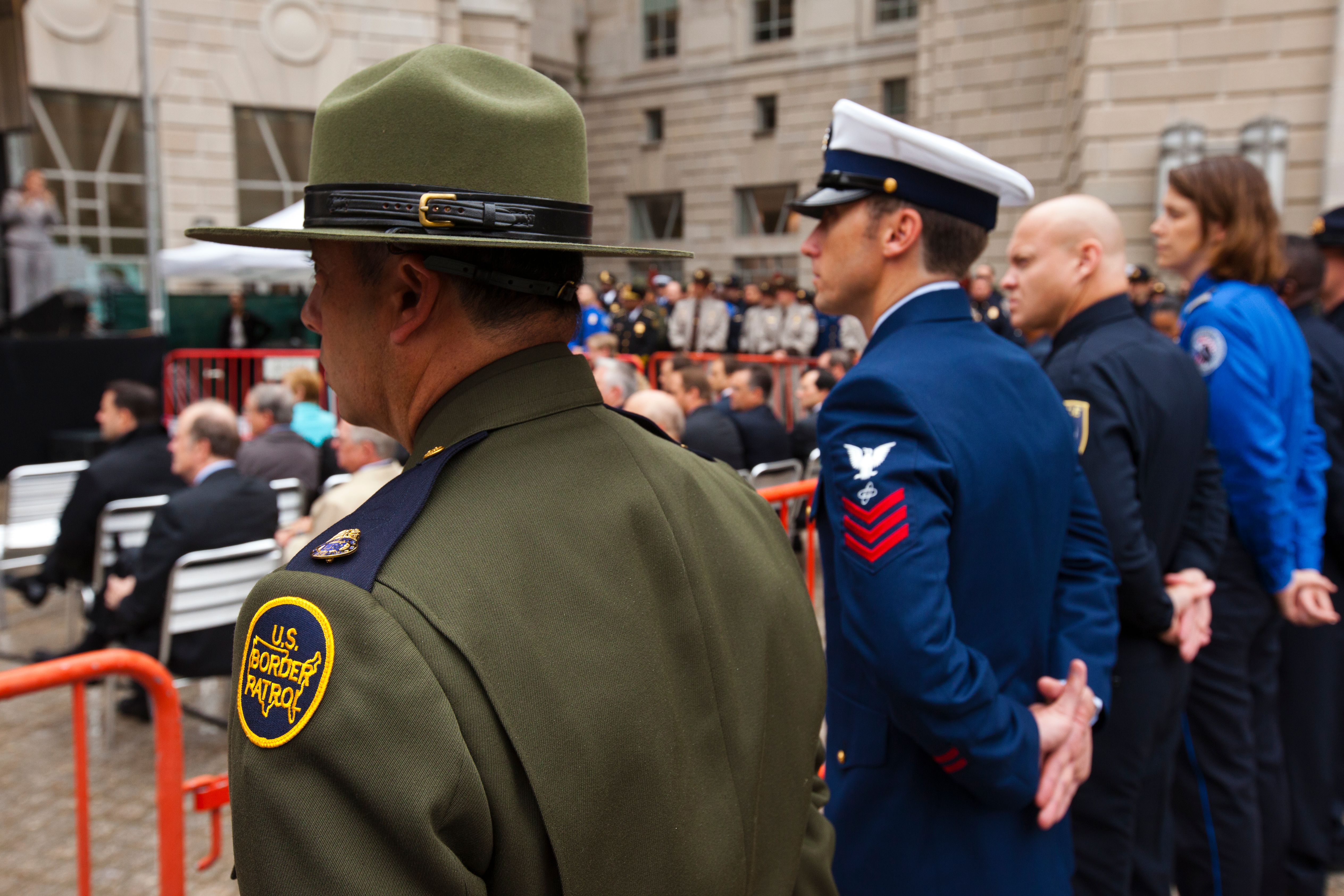 Uniformed officers stand at attention at an outdoor 9/11 memorial ceremony.