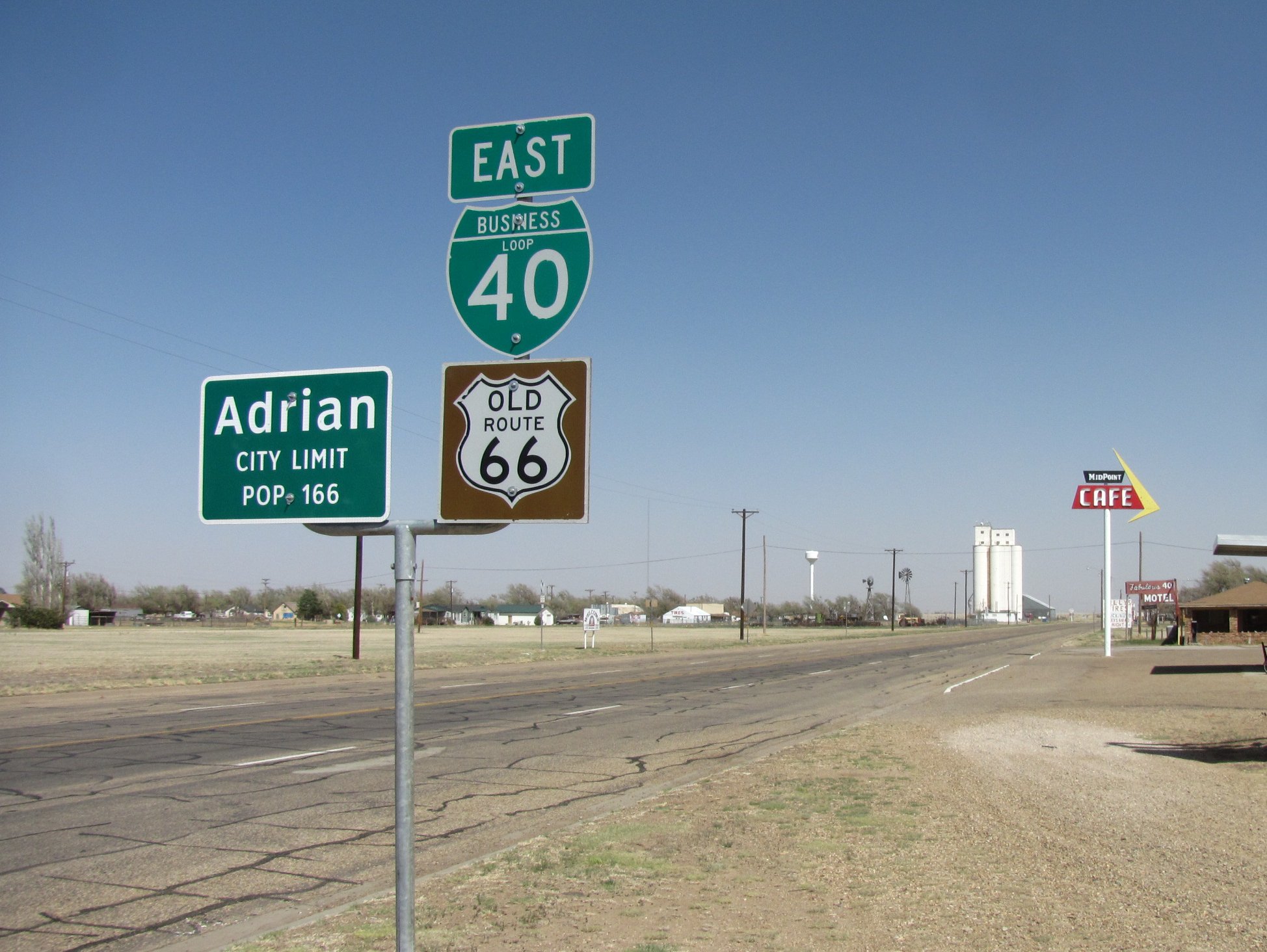 Old Route 66 shield sign posted along a flat rural highway under open sky.