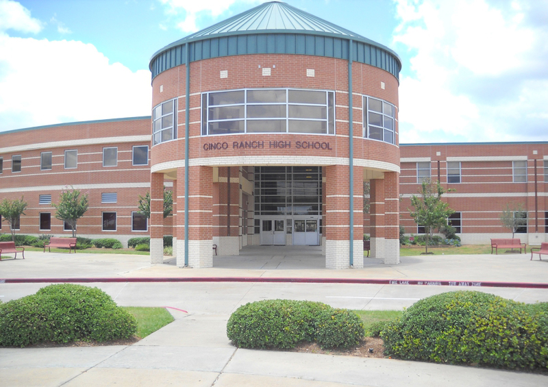 Brick school building with circular rotunda entrance and manicured shrubs.