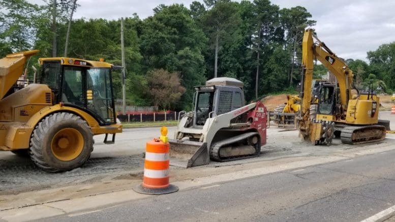 Yellow excavator, wheel loader, and track loader working at a road construction site.
