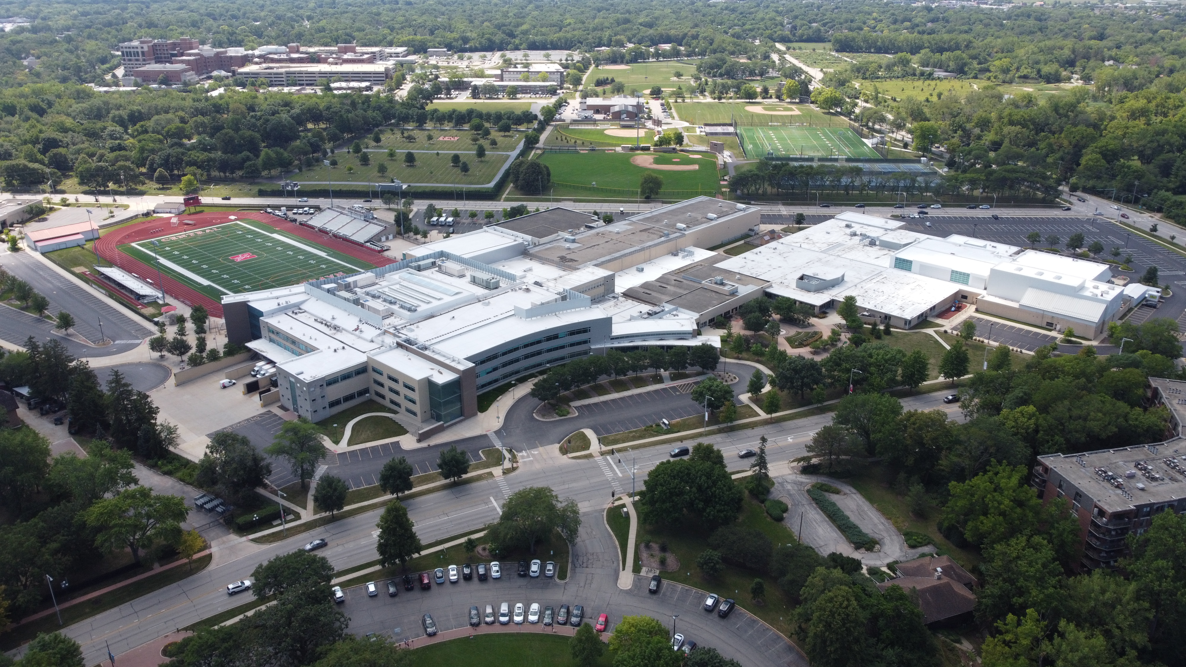 Aerial view of a large high school campus with a red-track football field and surrounding parking lots.