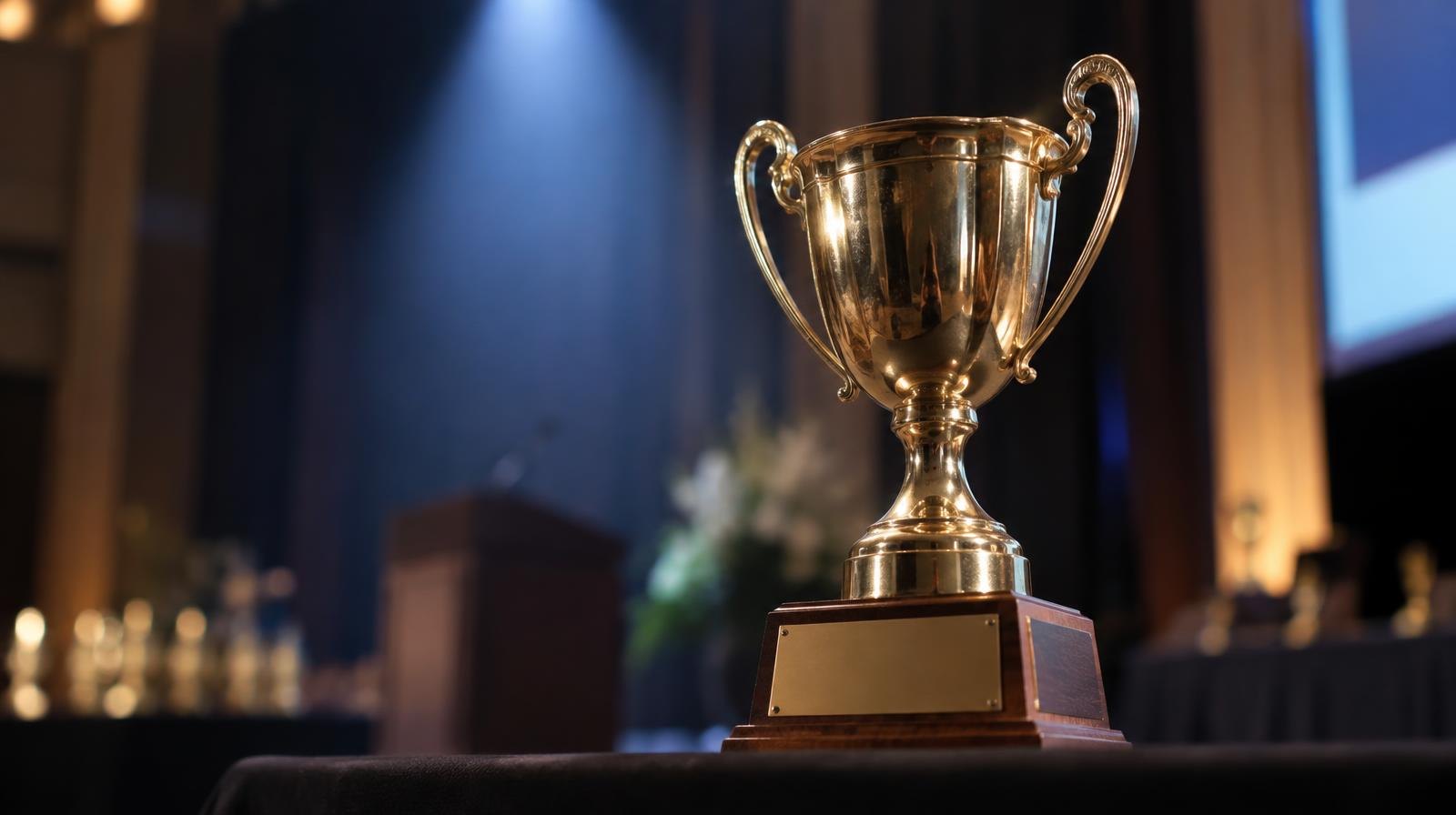 A gleaming trophy on a podium under a bright spotlight.