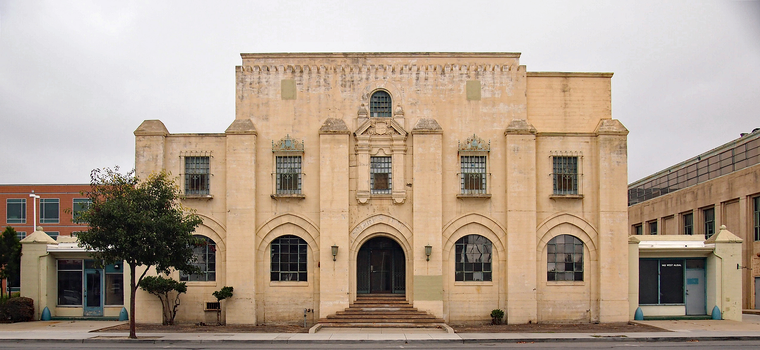 Two-story cream-colored historic jail building with arched entryways and decorative stonework.