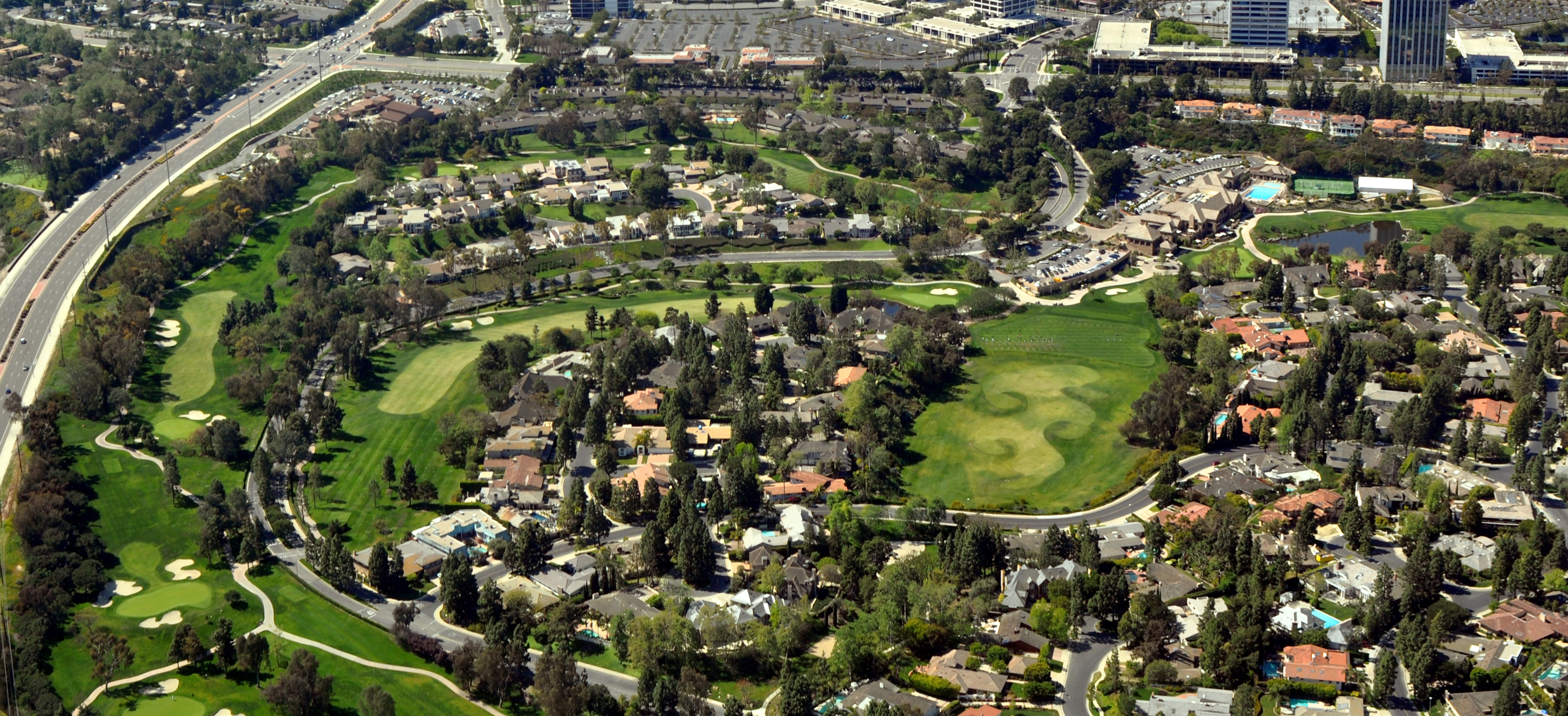 Aerial view of a golf course surrounded by residential neighborhoods and a freeway.