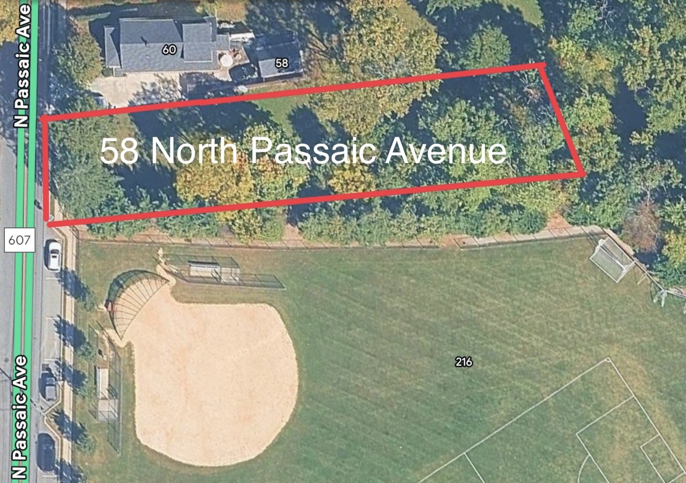 Aerial satellite view of a wooded parcel outlined in red next to a baseball field and park.