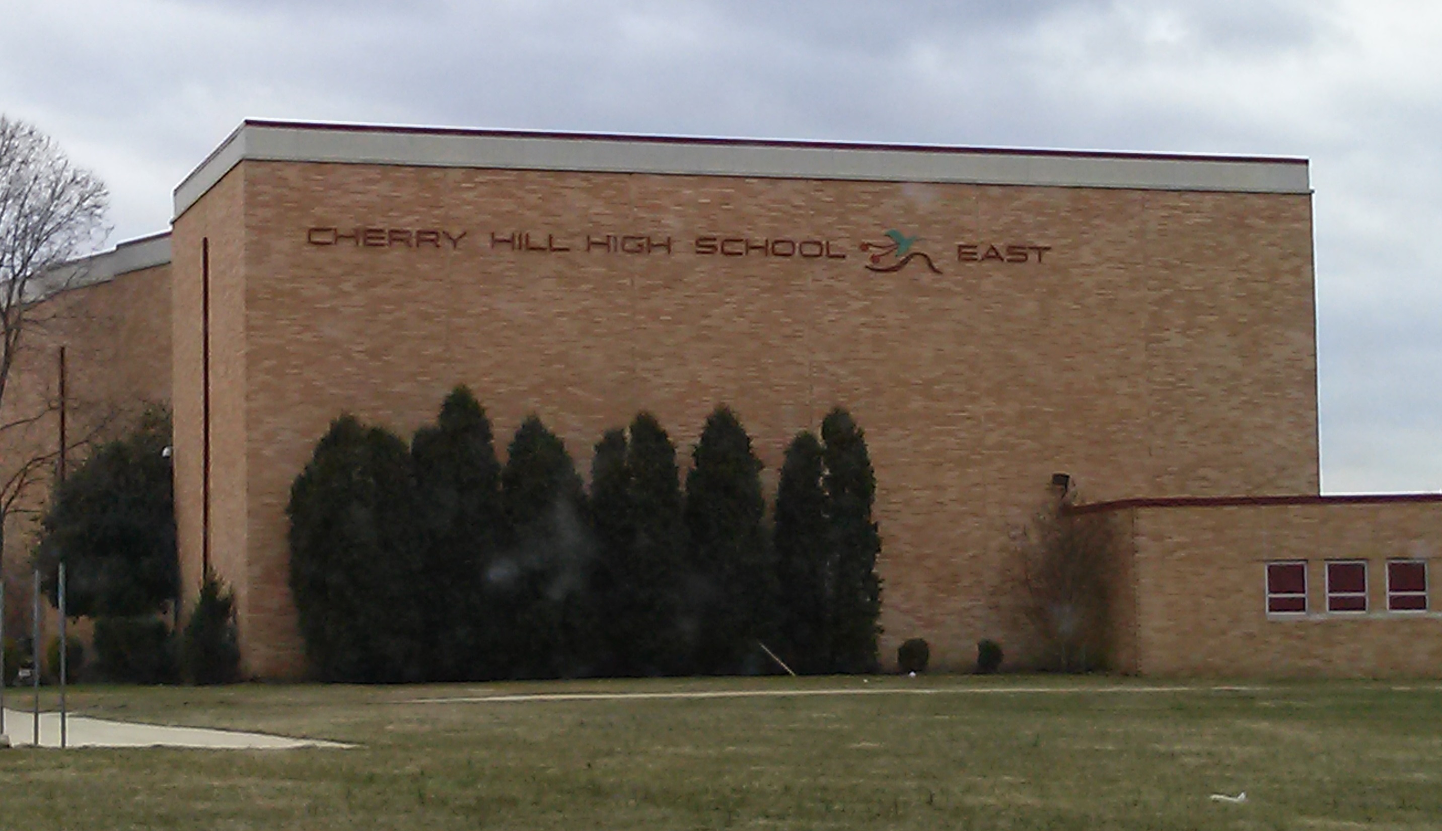 Brick facade of a high school building with the school name and logo displayed at the entrance.