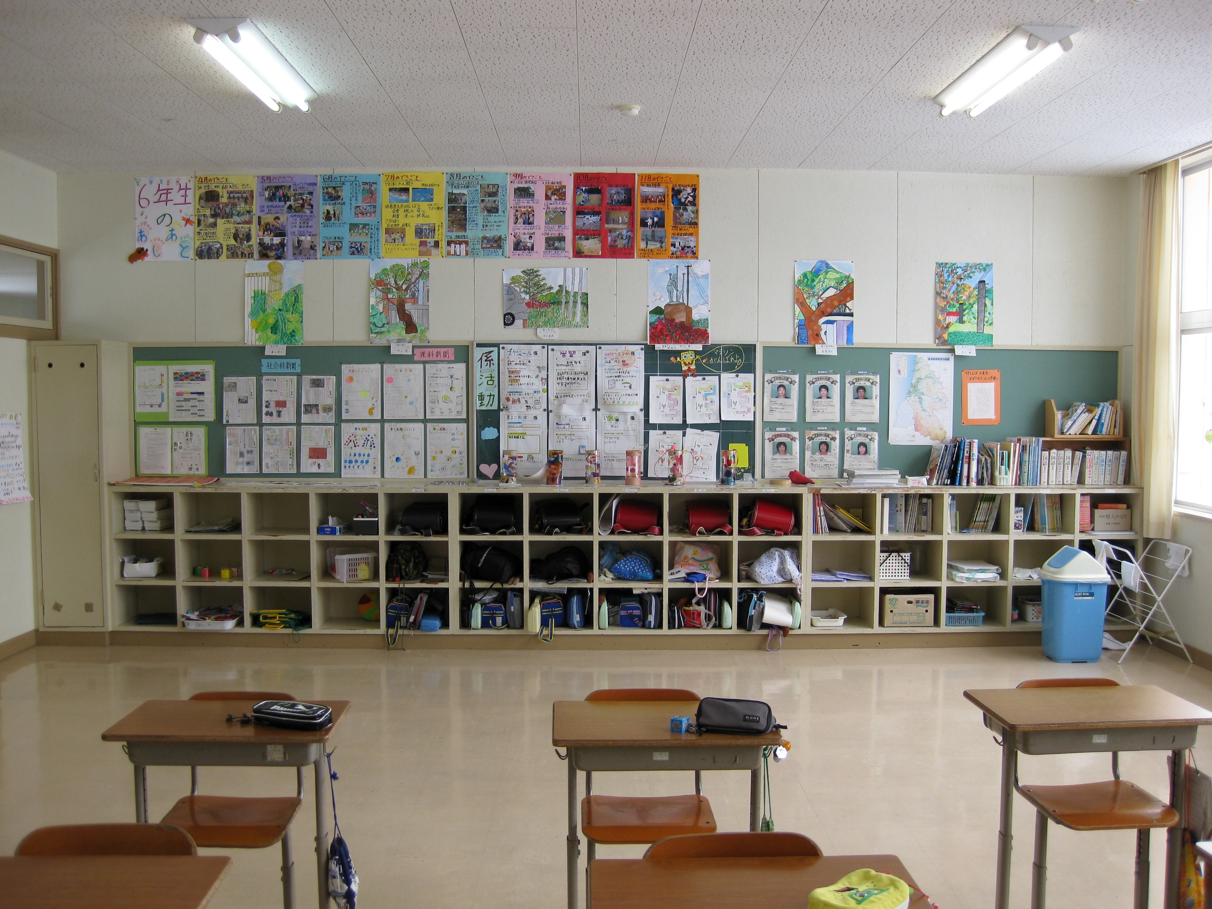 Elementary classroom with student cubbies, colorful artwork, and desks in the foreground.