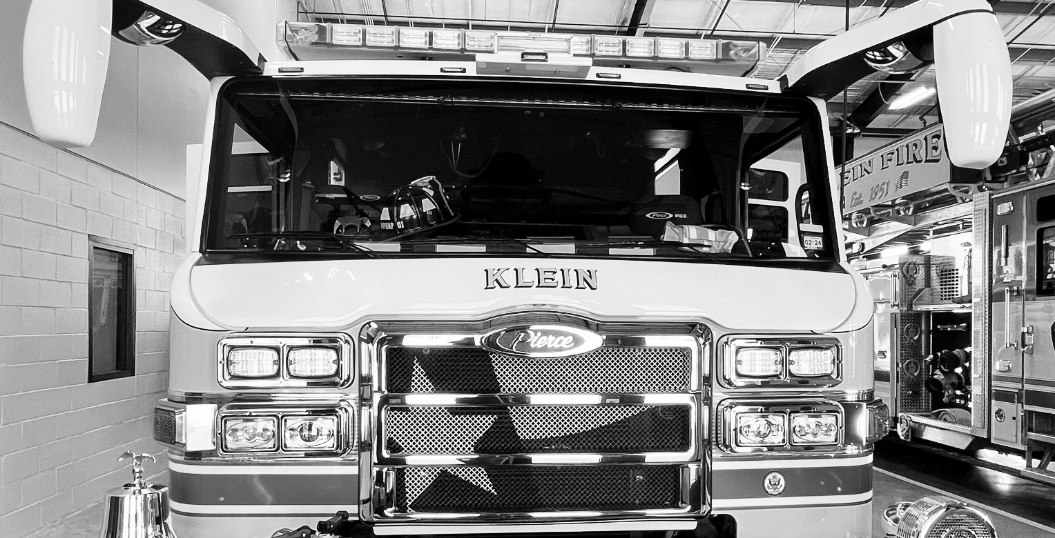Black-and-white front view of a fire engine labeled Klein inside a station bay.