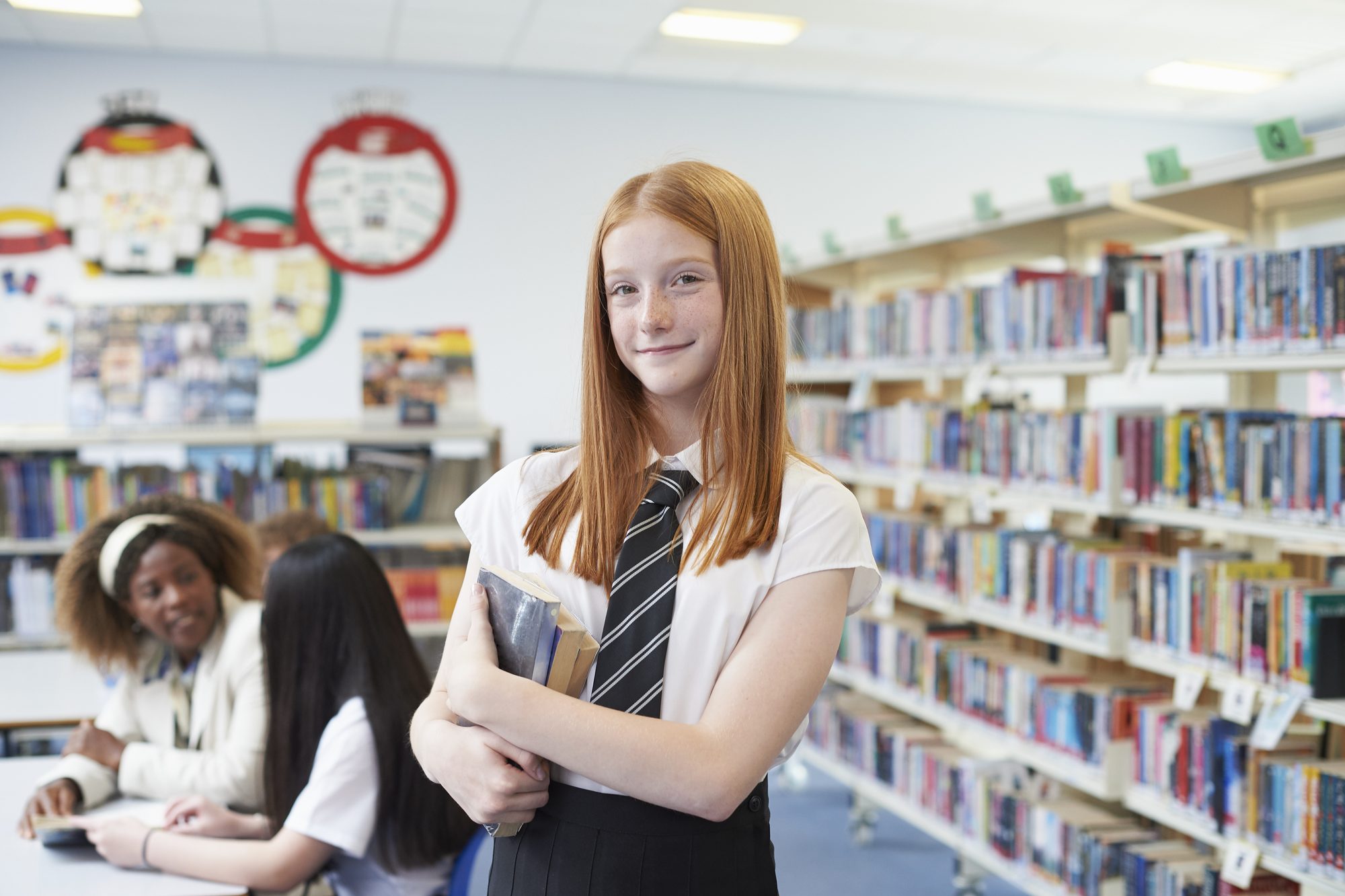 Portrait of a schoolgirl holding books in a high school library