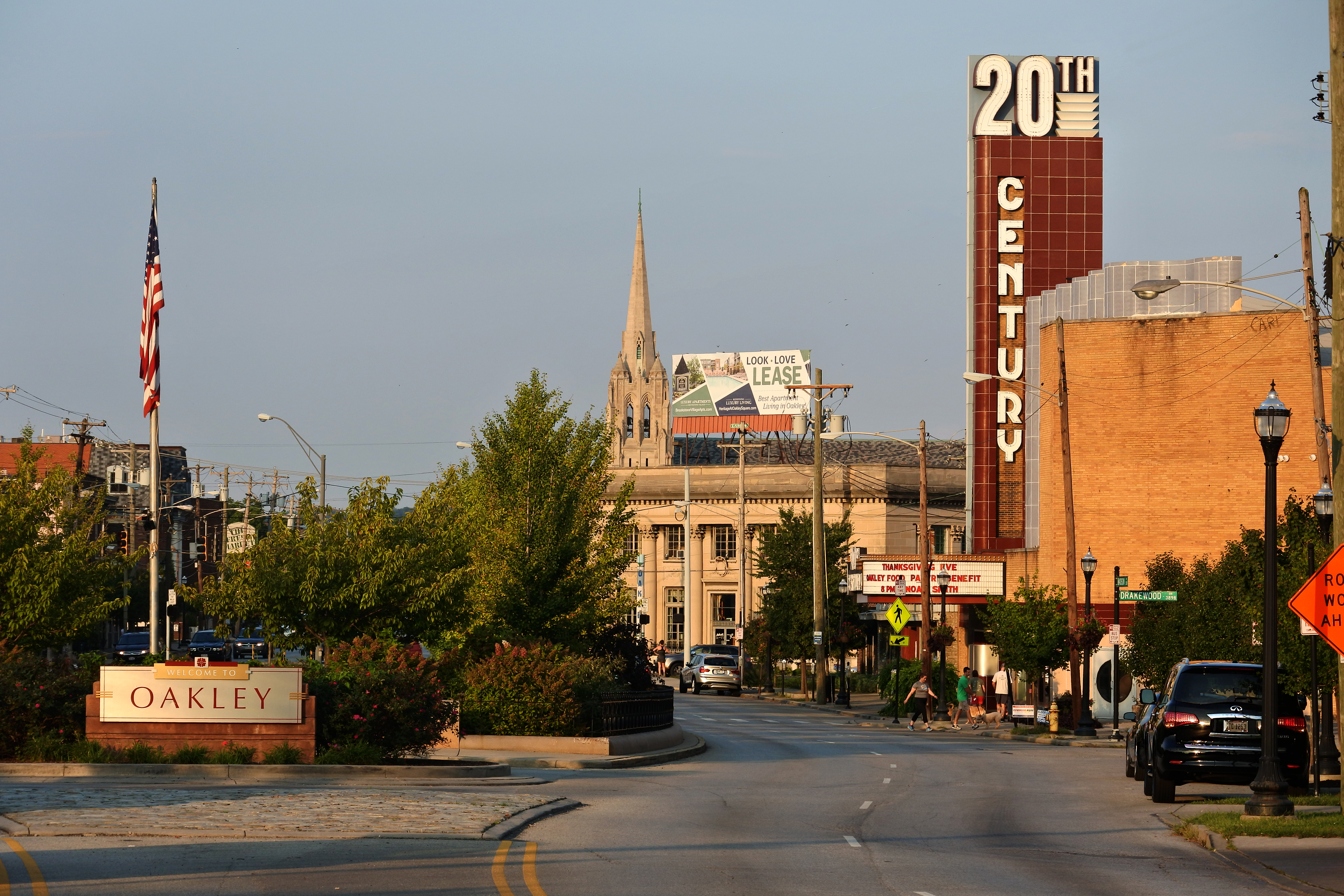 Street-level view of Oakley Square commercial corridor with storefronts and neighborhood sign.
