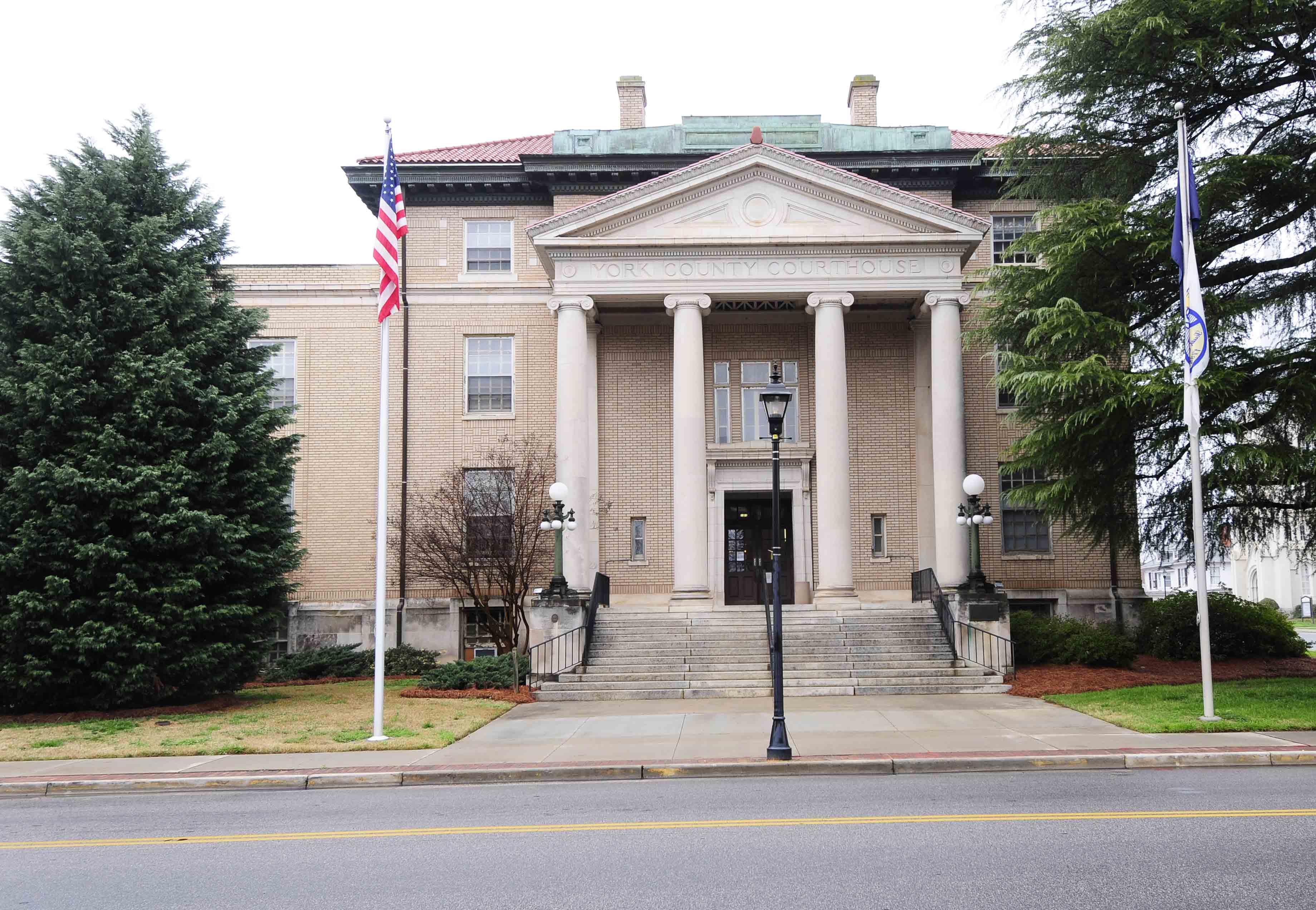 Neoclassical brick courthouse with white columns and flags out front.