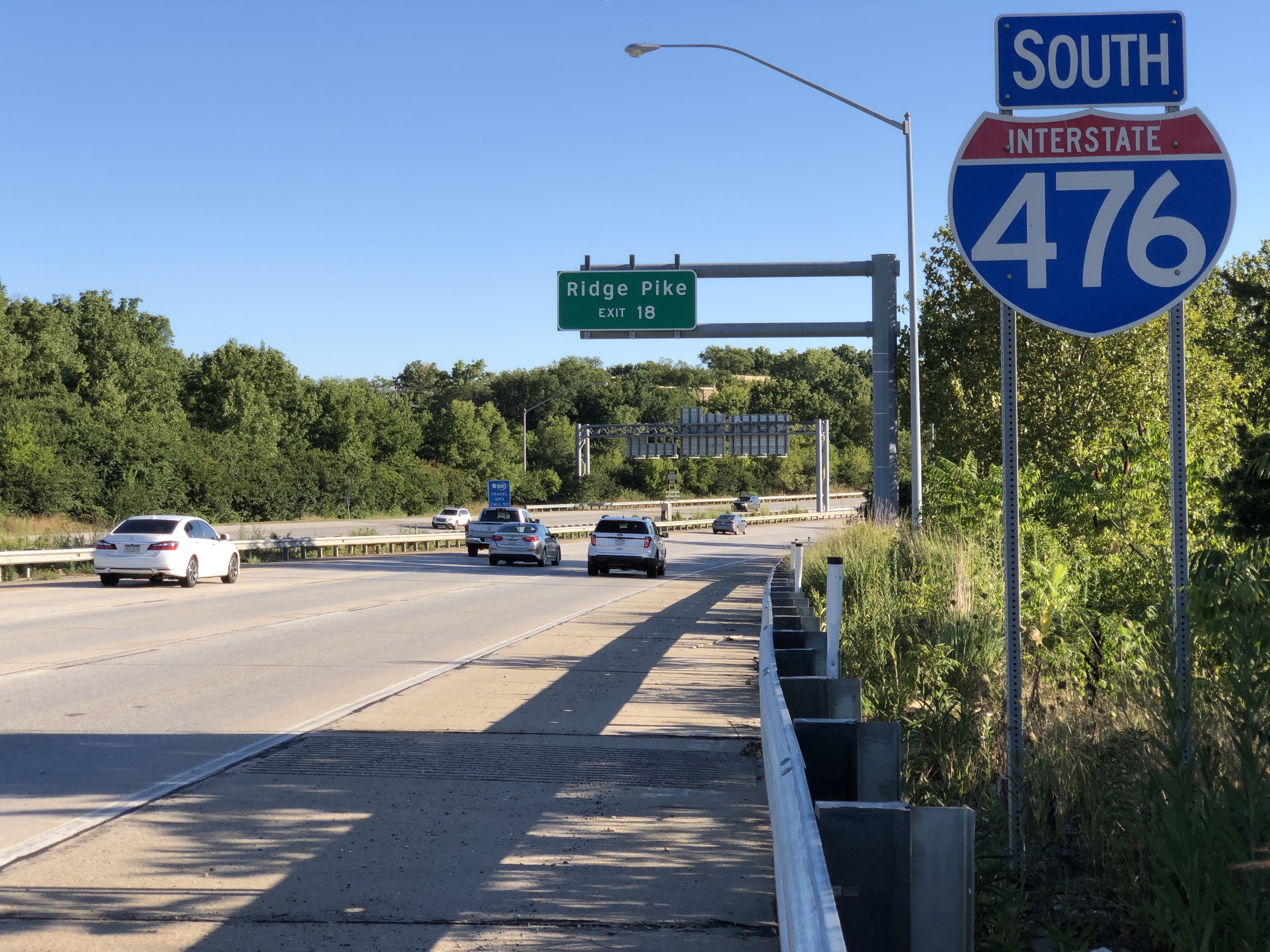 Southbound lanes of Interstate 476 with an overhead highway sign and light traffic.