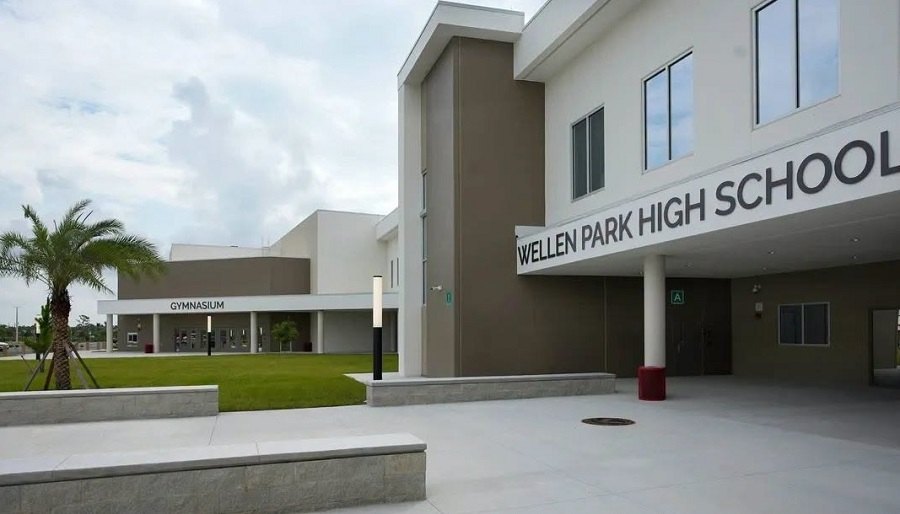 Exterior of a modern two-story high school building with signage and palm trees.