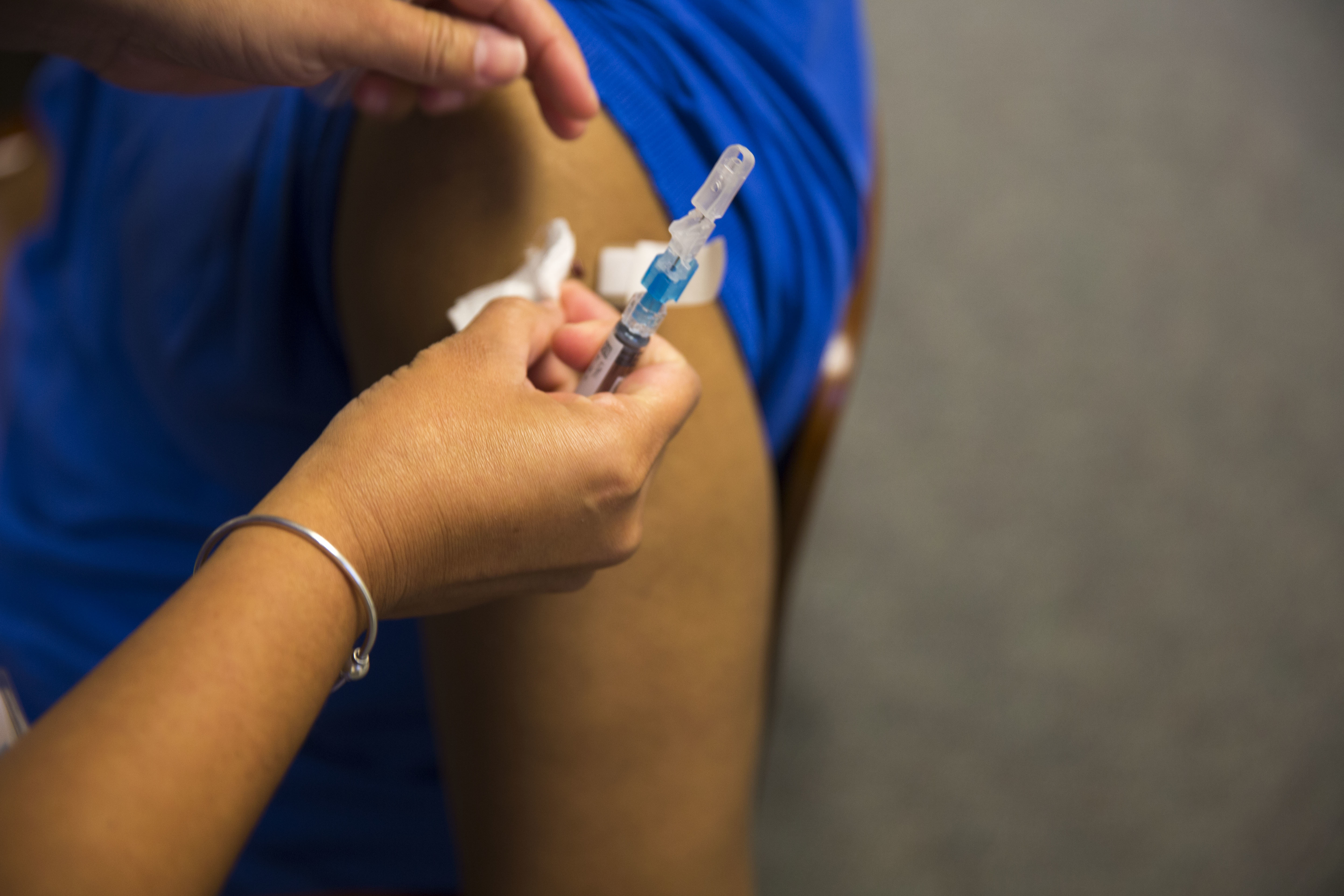 Healthcare worker placing a bandage on a patient's upper arm after an injection.