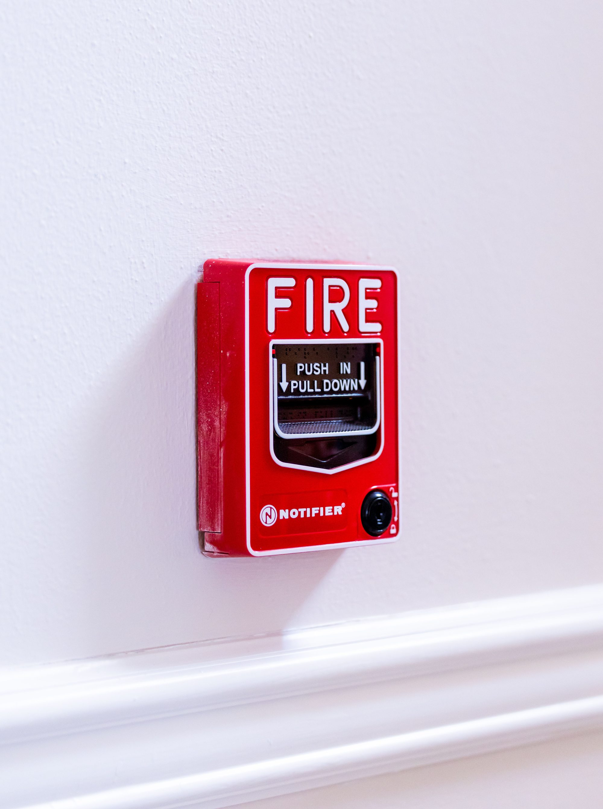 Close-up view of a red fire alarm switch with clear text instructions on a white wall.