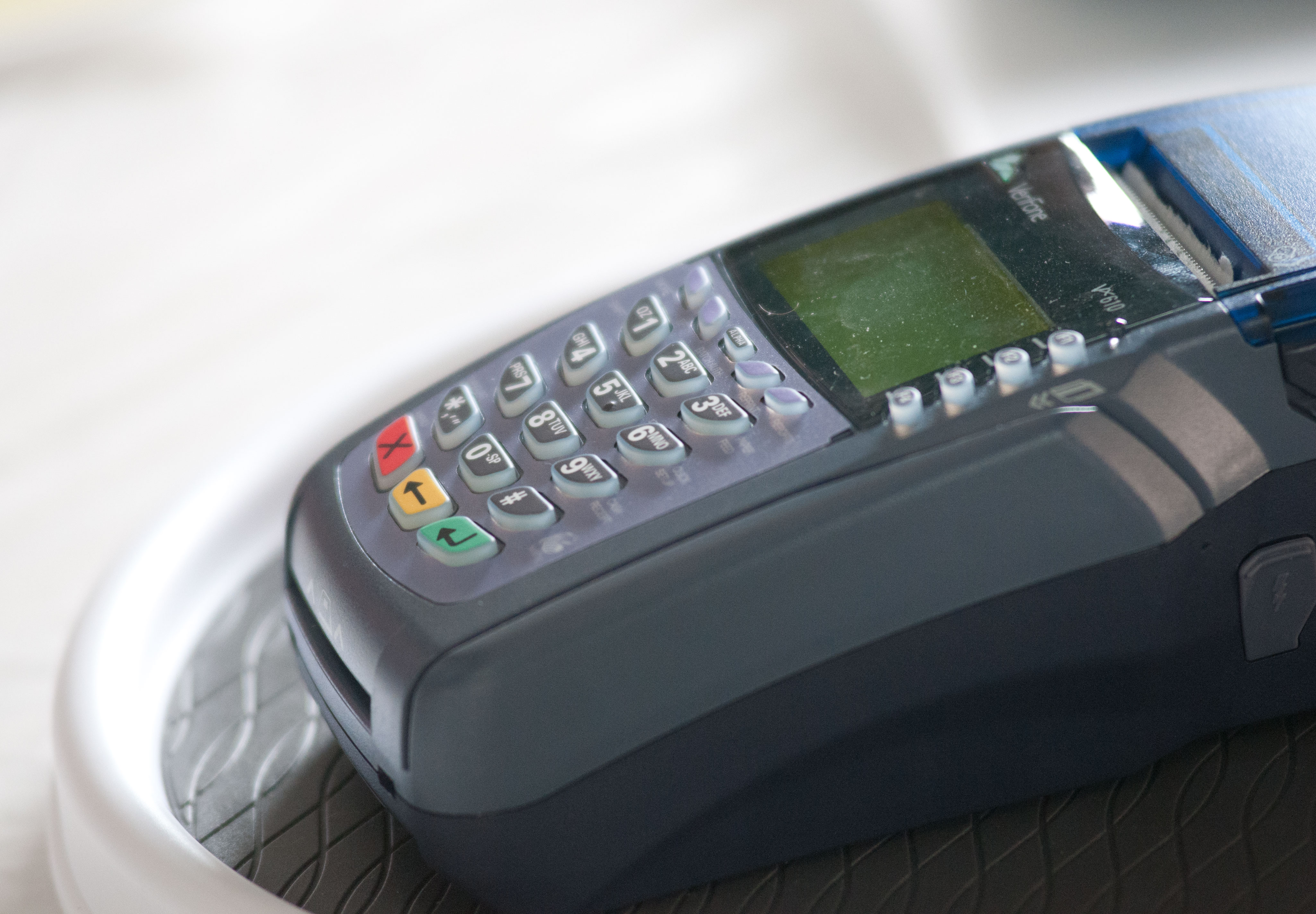 A gray wireless card reader terminal with a numeric keypad and small display screen.