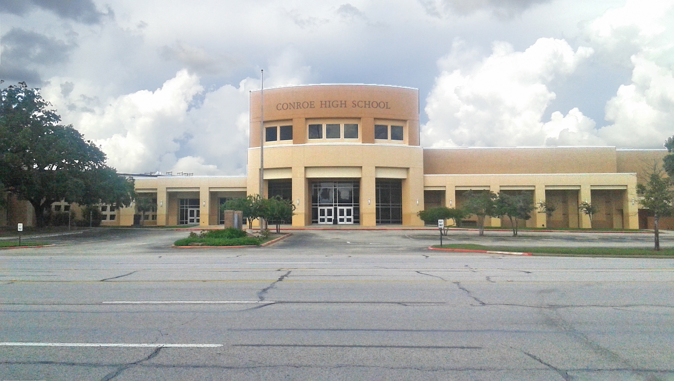 Exterior of a tan brick high school building with the school name above the main entrance.