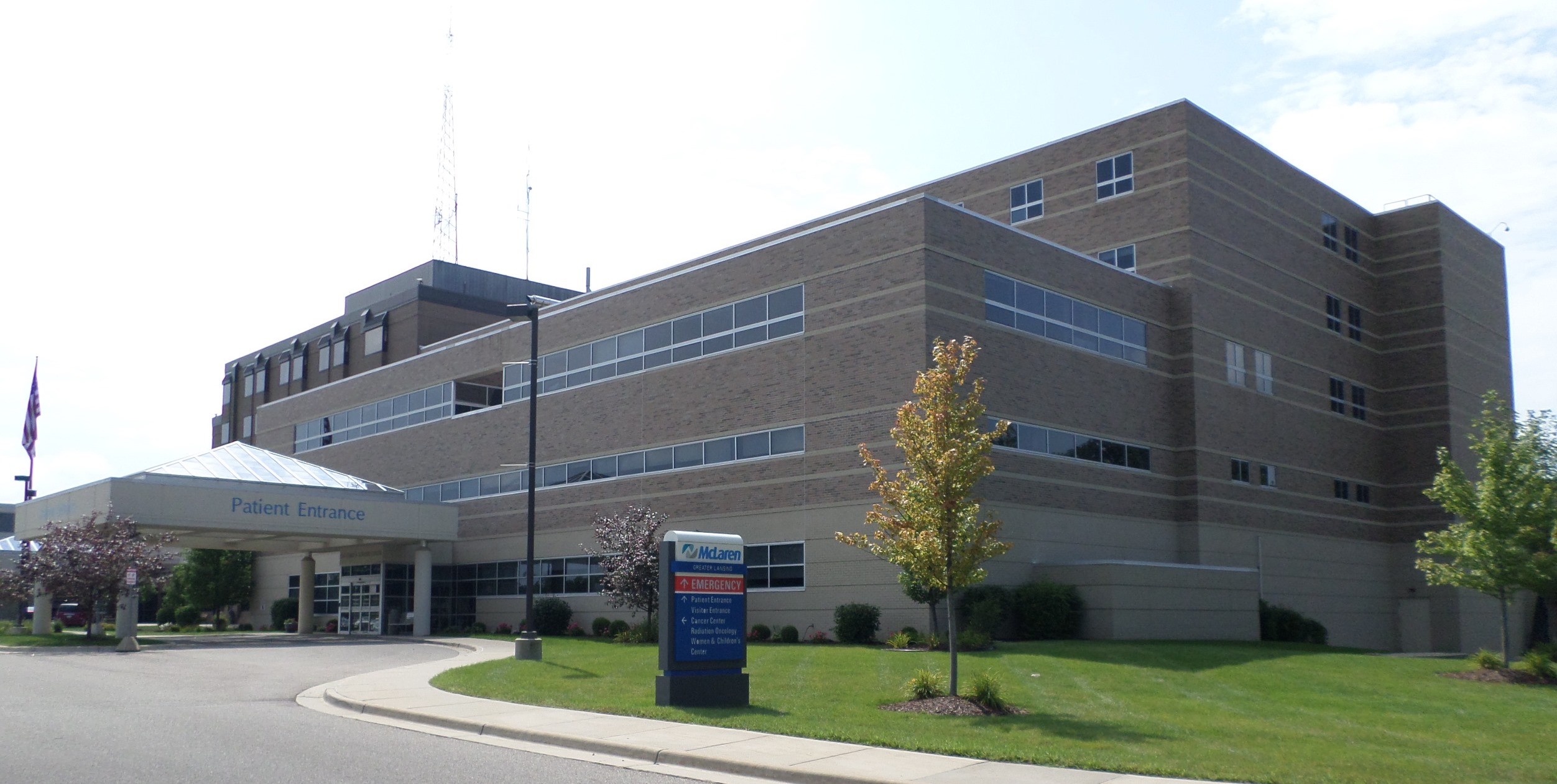 Multi-story brick hospital building with a covered patient entrance and blue McLaren sign.