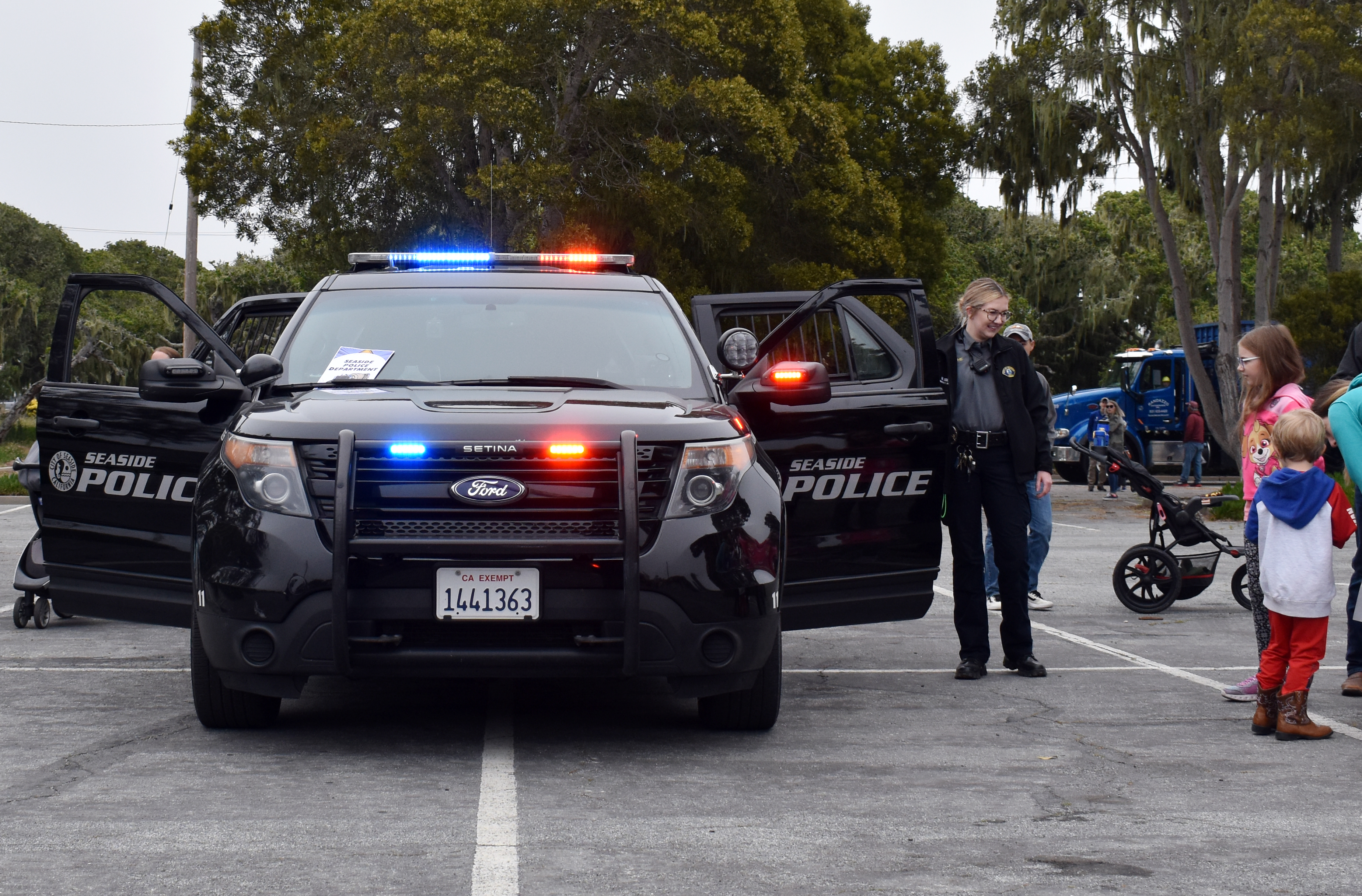 Two black police SUVs marked Seaside Police Department parked at an outdoor community event.