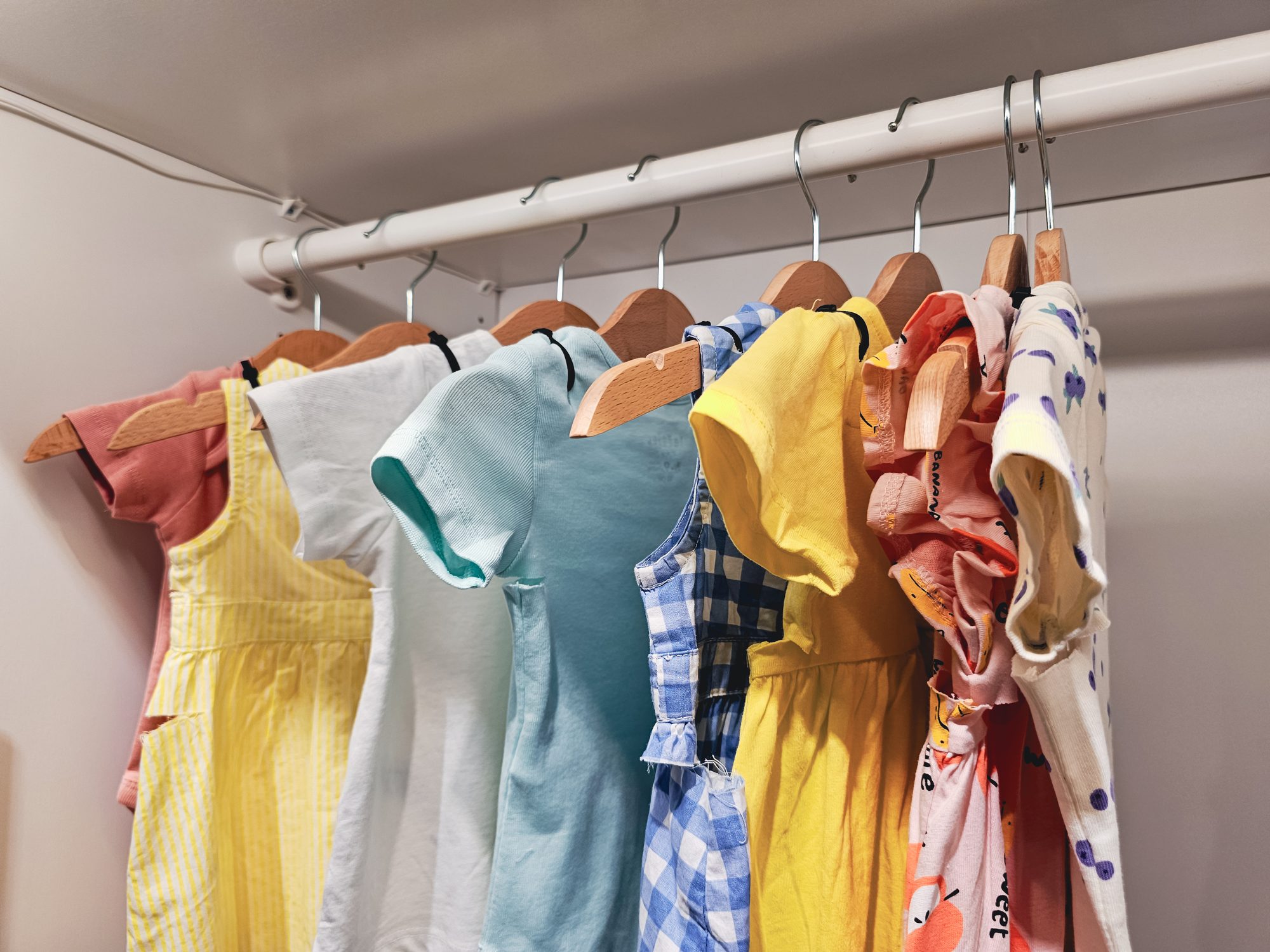 Elegant Wardrobe with kids clothes on Hangers in Wooden Closet