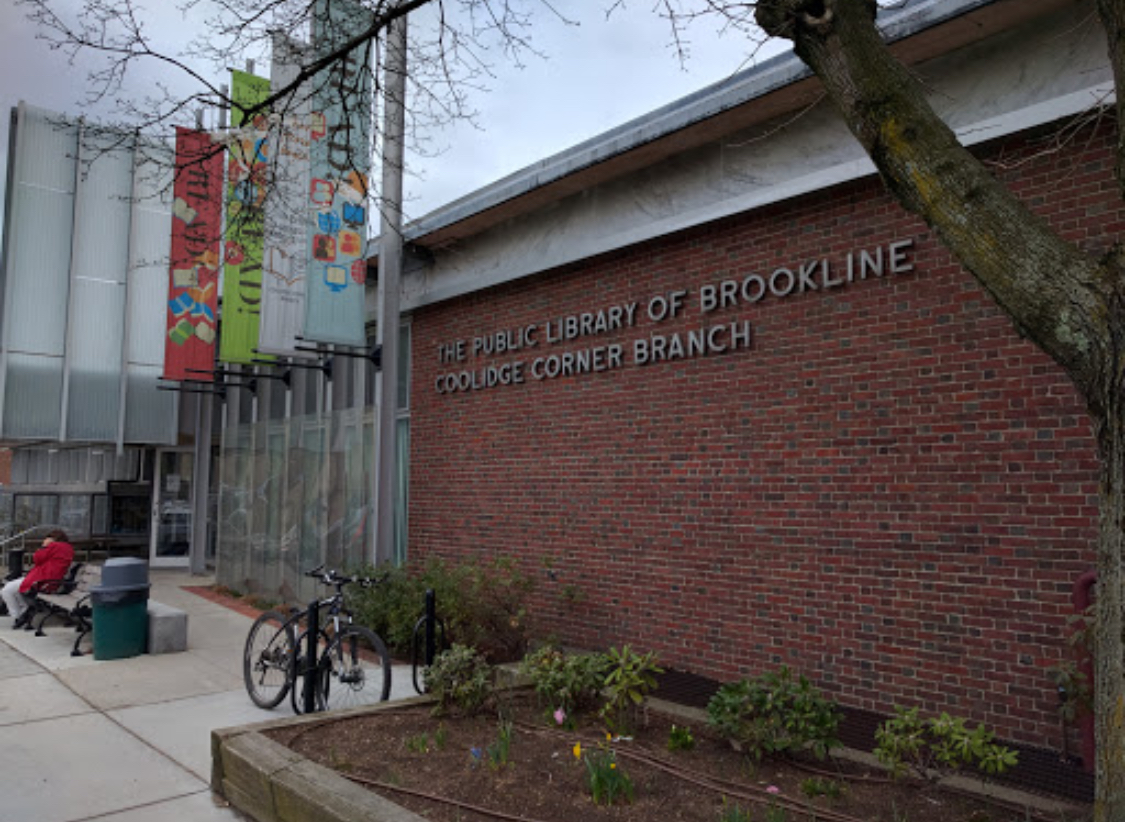 Red brick library building with colorful banners and a bicycle parked outside.