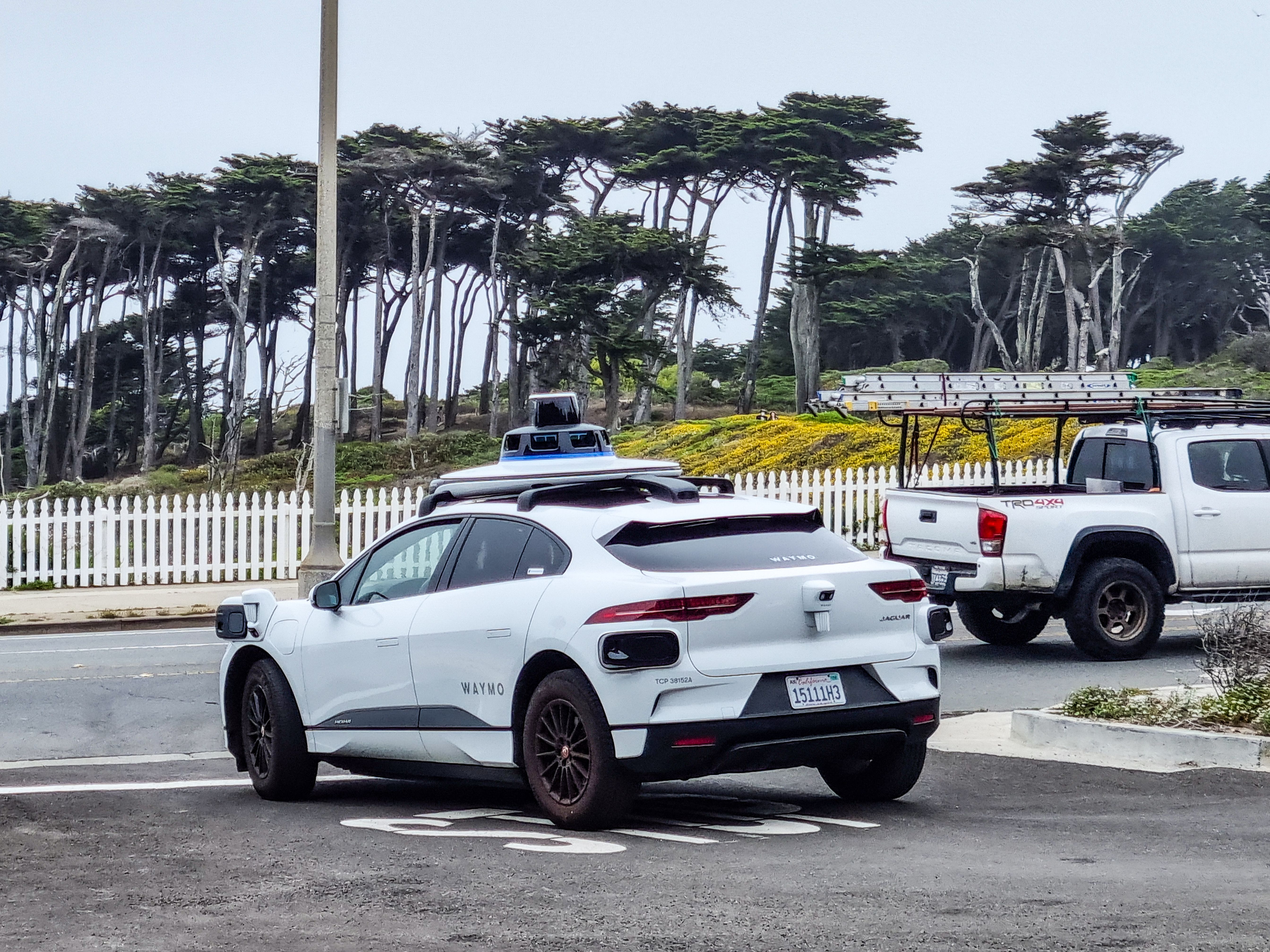 White Waymo robotaxi with lidar sensor dome on roof, parked in a lot