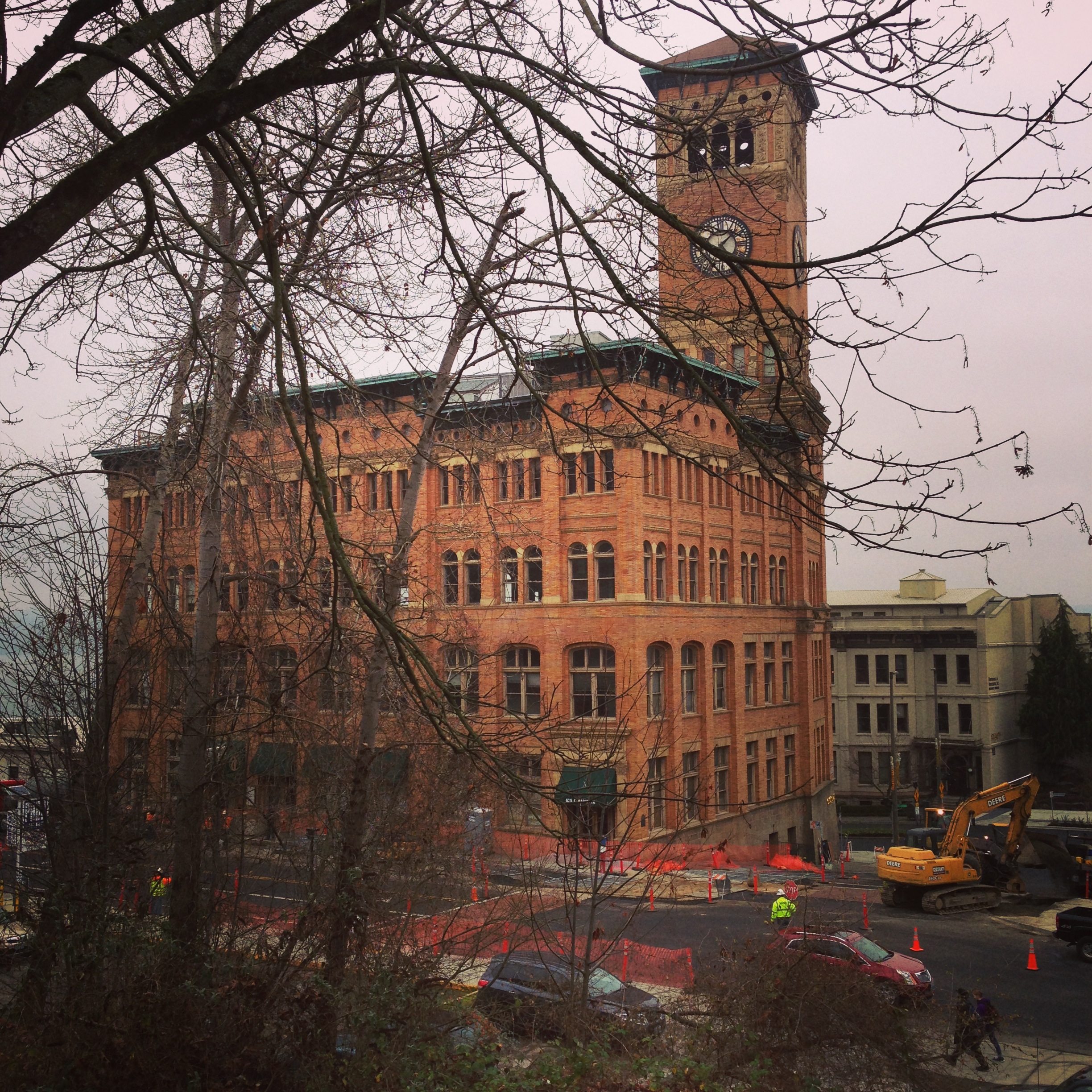 Historic brick building with clock tower and construction equipment at street level in Tacoma.