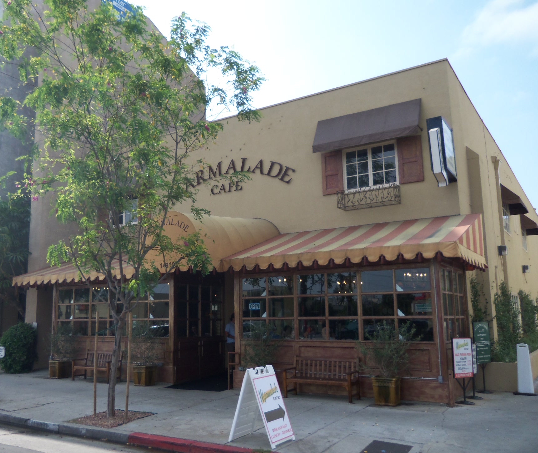 Restaurant exterior with yellow and white striped awning and sidewalk sandwich board sign.