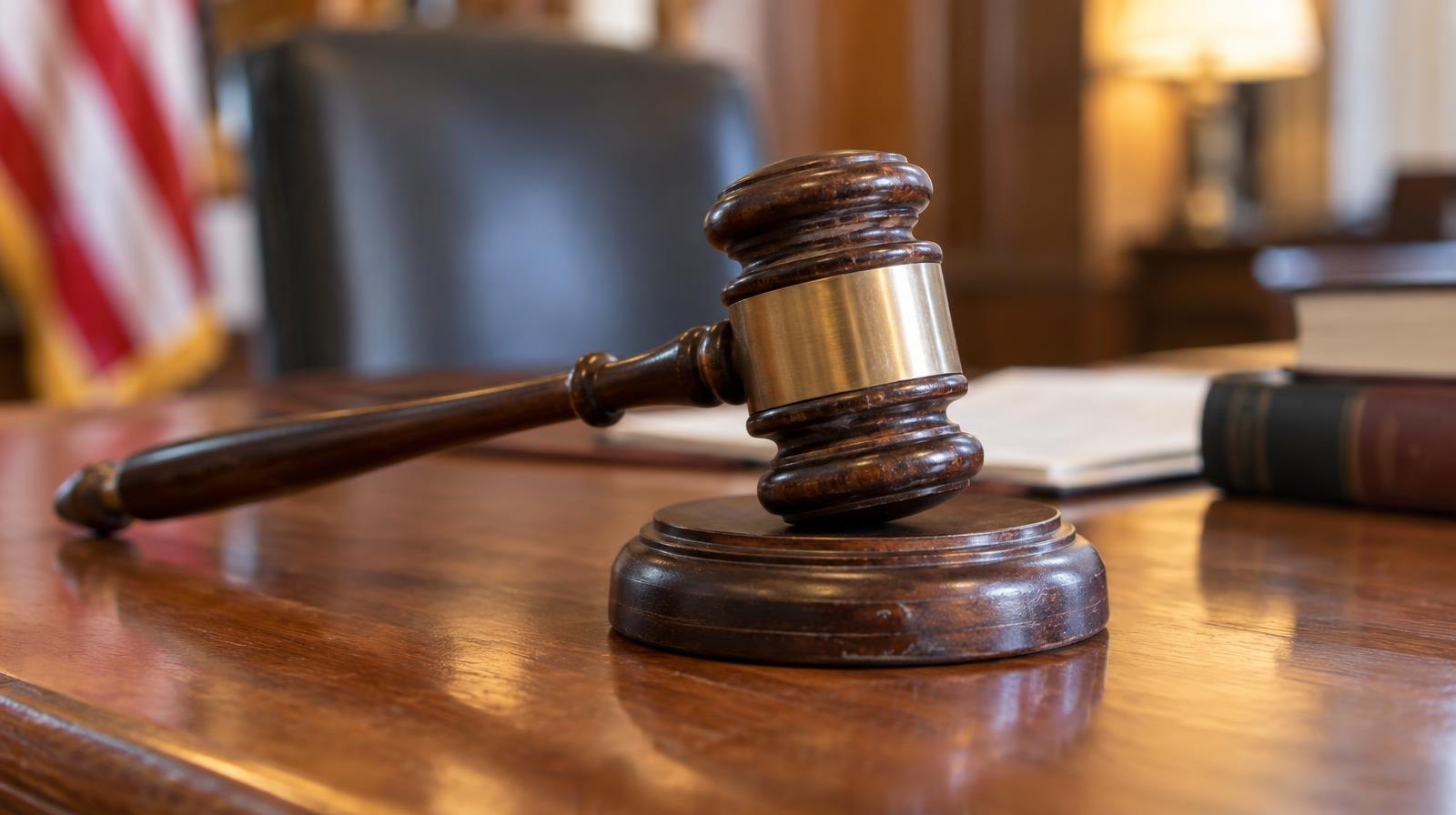 Wooden judge's gavel resting on its sound block on a polished surface.
