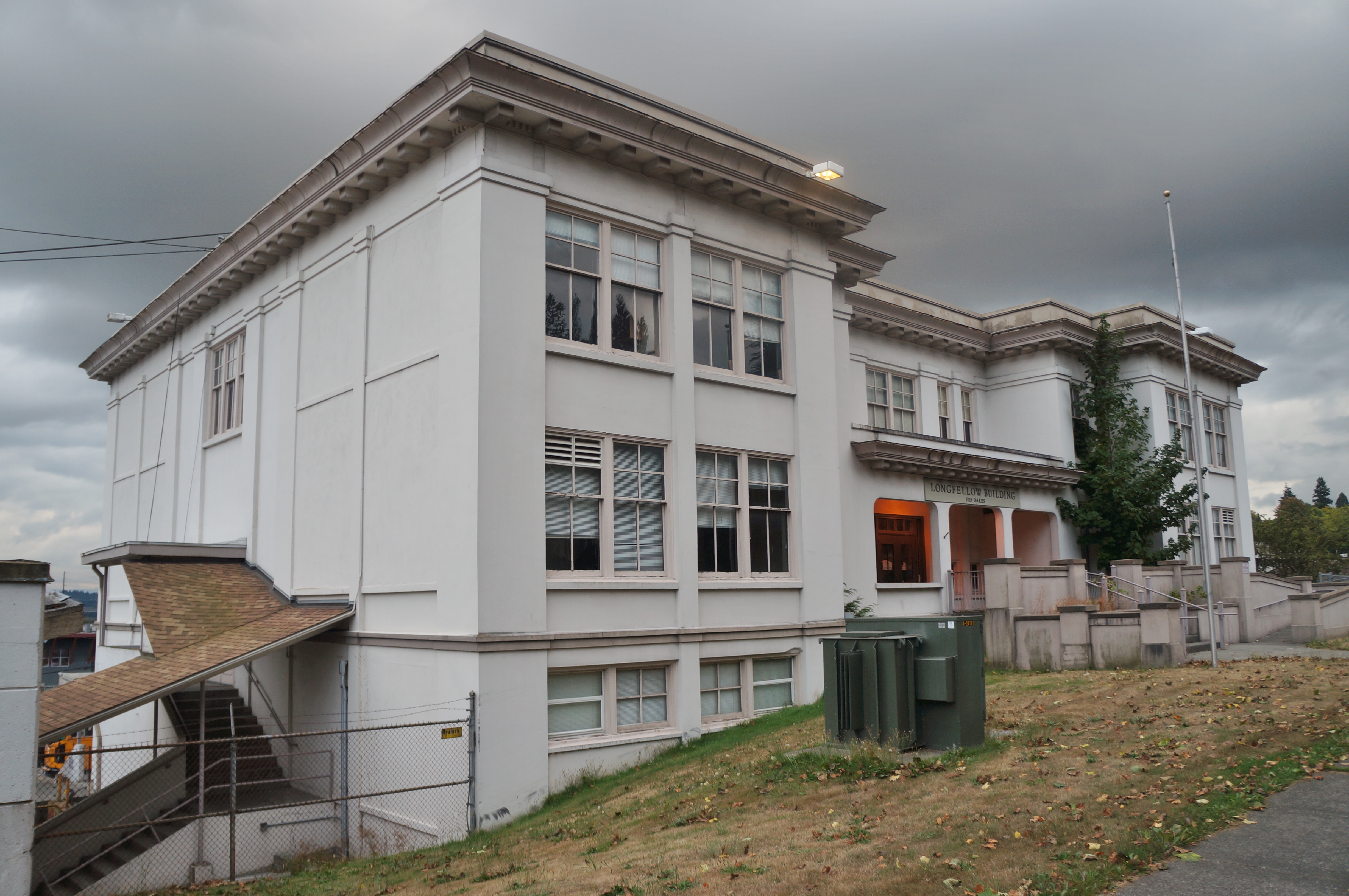 Two-story white historic school building with classical architectural details under an overcast sky.
