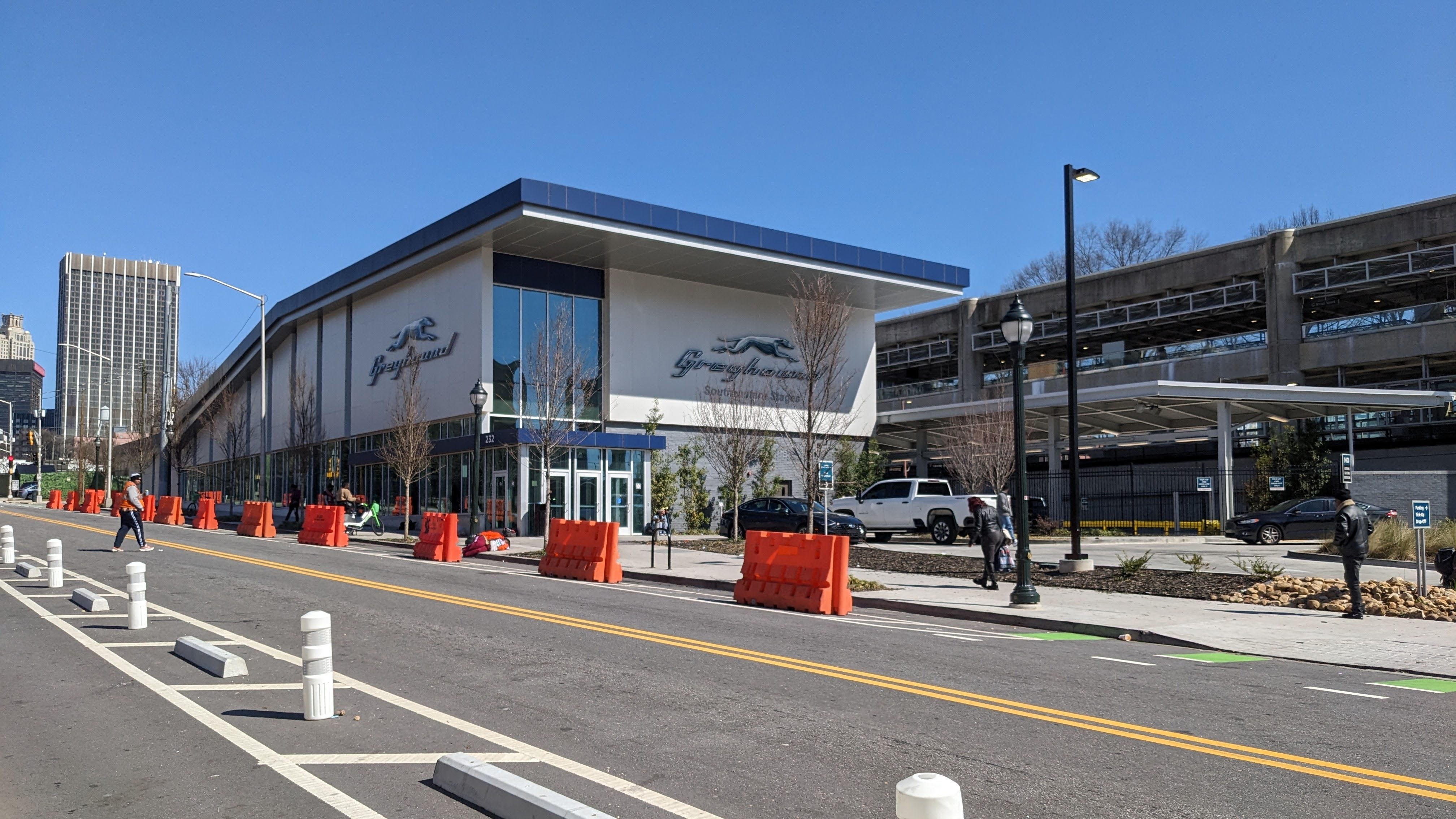 Exterior of the Greyhound bus station in Atlanta with glass windows and orange traffic barriers along the road.