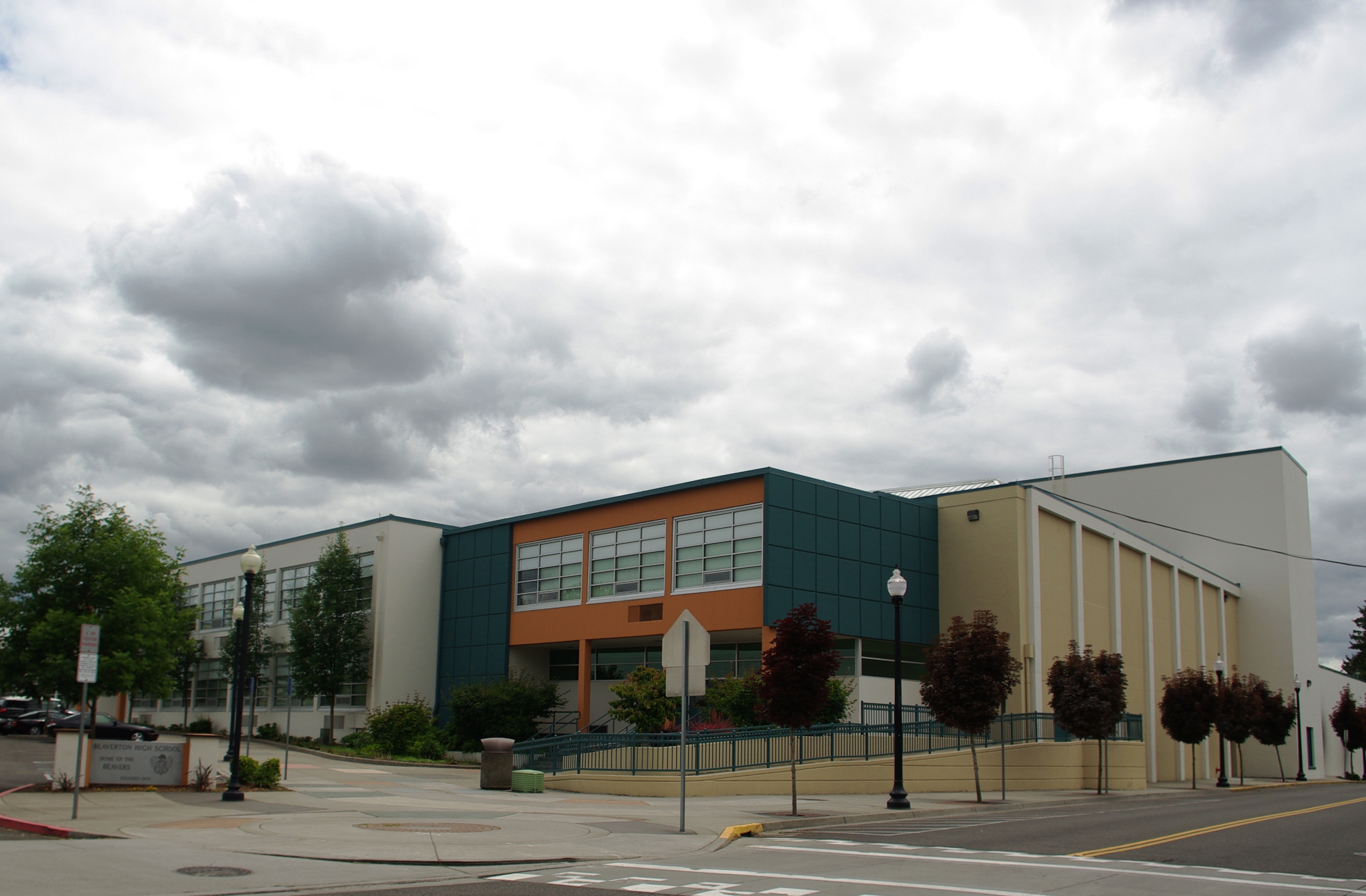 Exterior facade of a two-story school building with teal and orange cladding.
