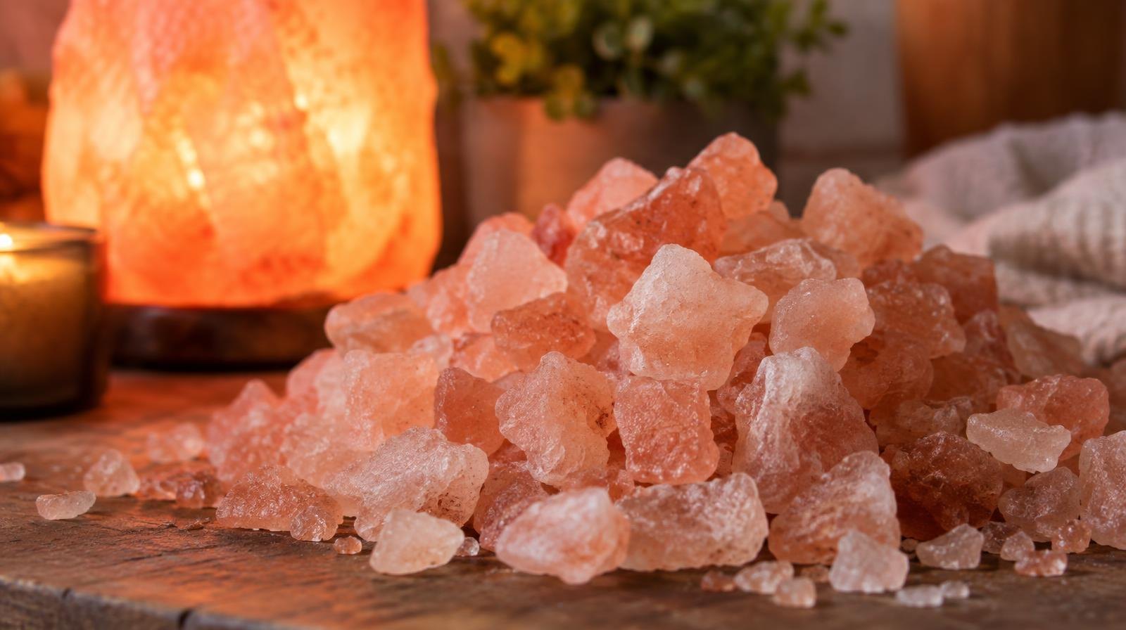 Close-up of coarse pink salt crystals bathed in warm red light.