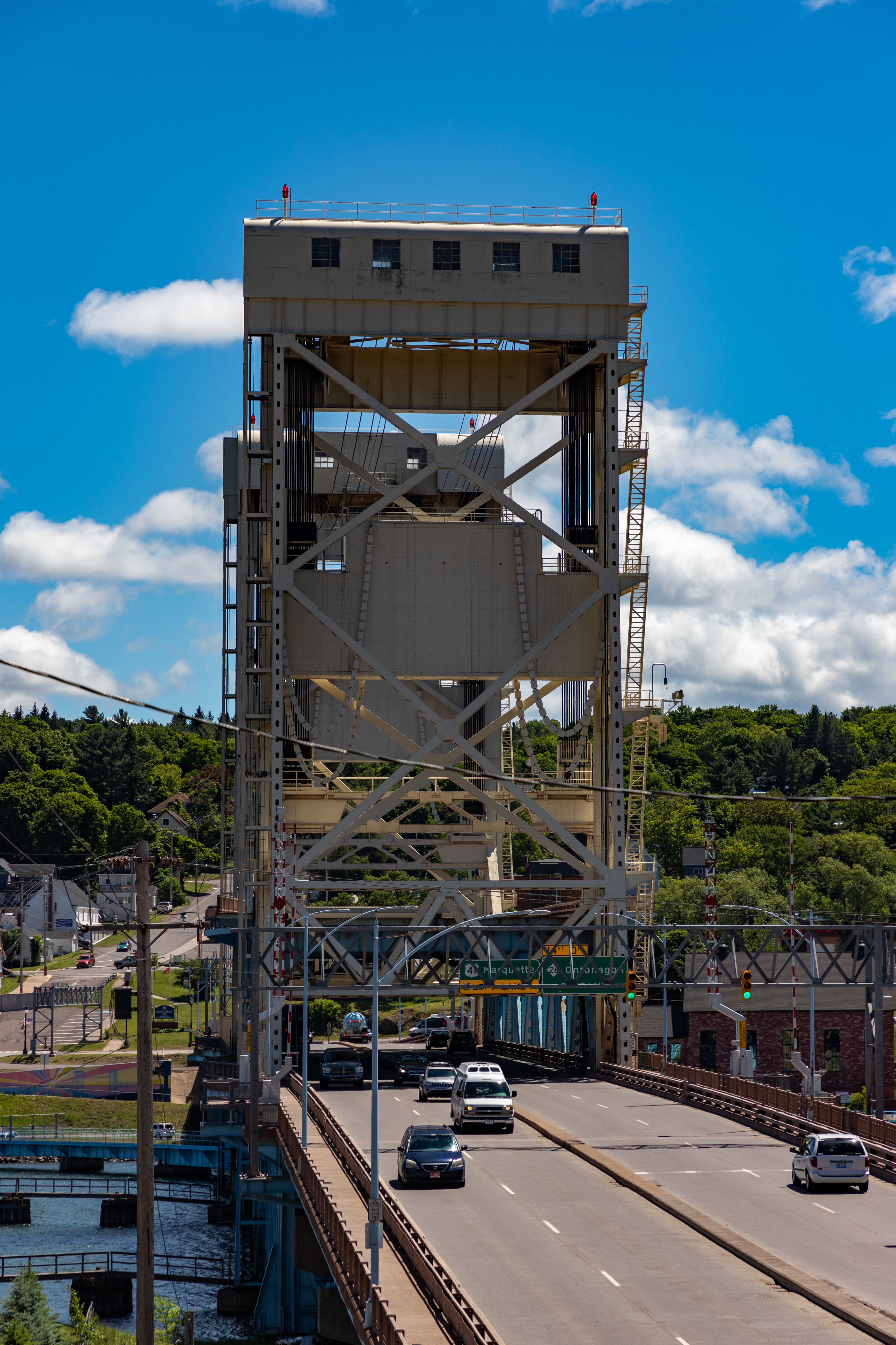 Vertical-lift bridge with tall tower and vehicles crossing over a calm waterway.