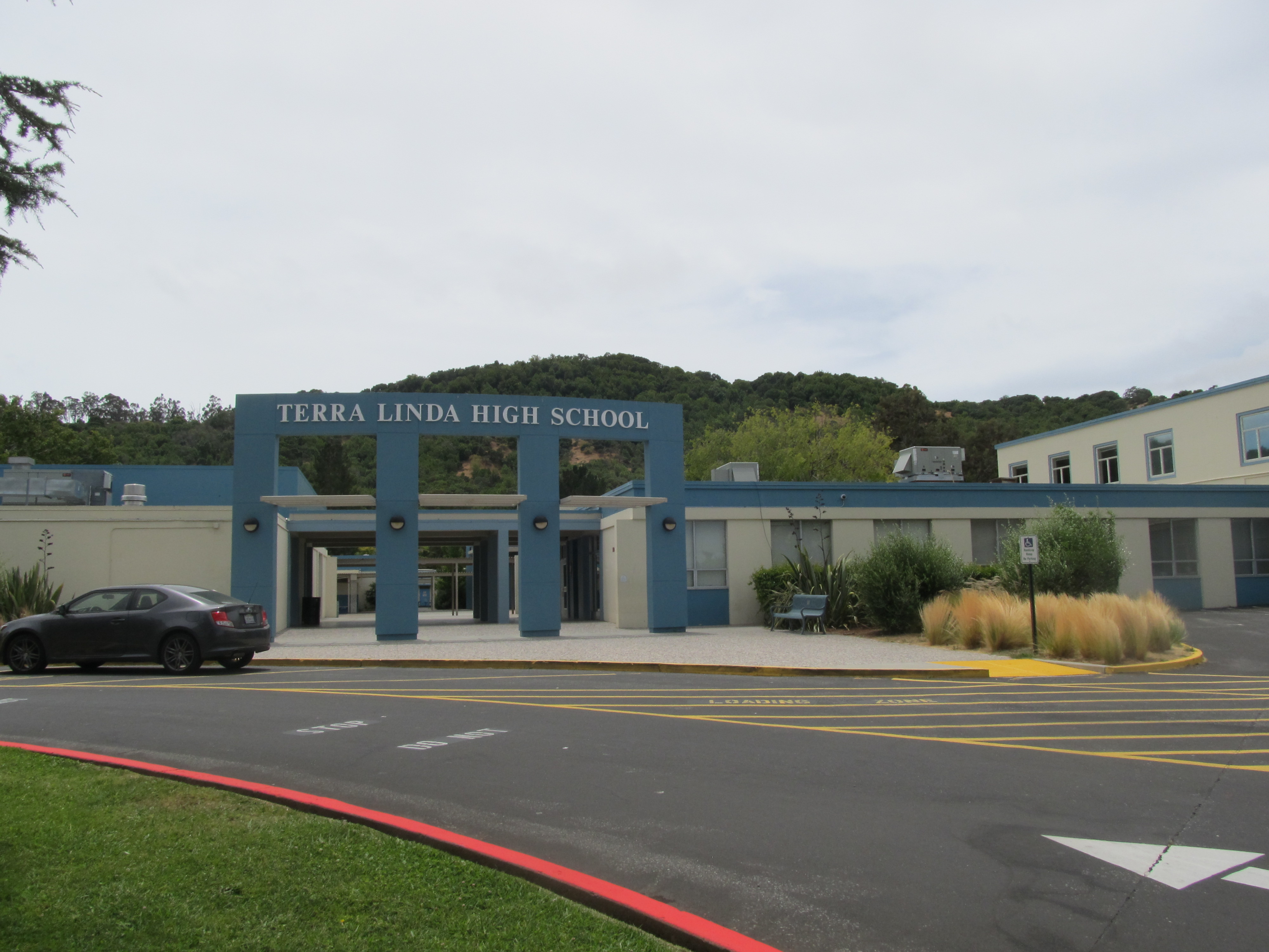 Blue and tan school building entrance with a sign reading Terra Linda High School and a parking lot in front.