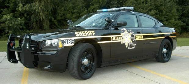 Black Oakland County Sheriff Dodge Charger patrol car parked in a lot.