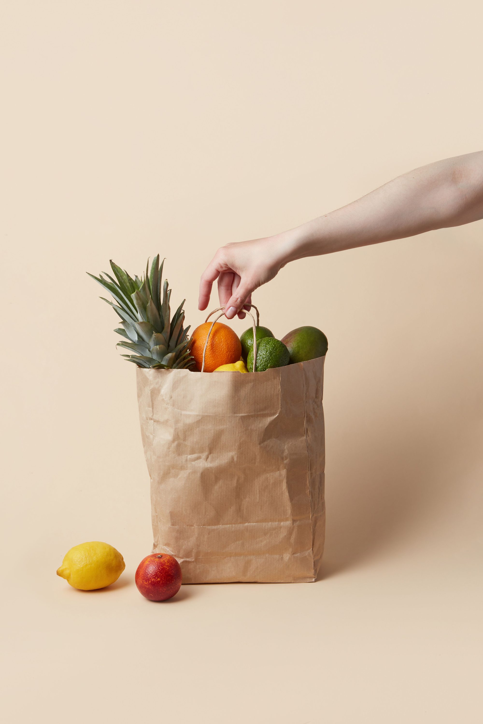 A hand reaches for organic fruits in a paper bag, showcasing fresh groceries.