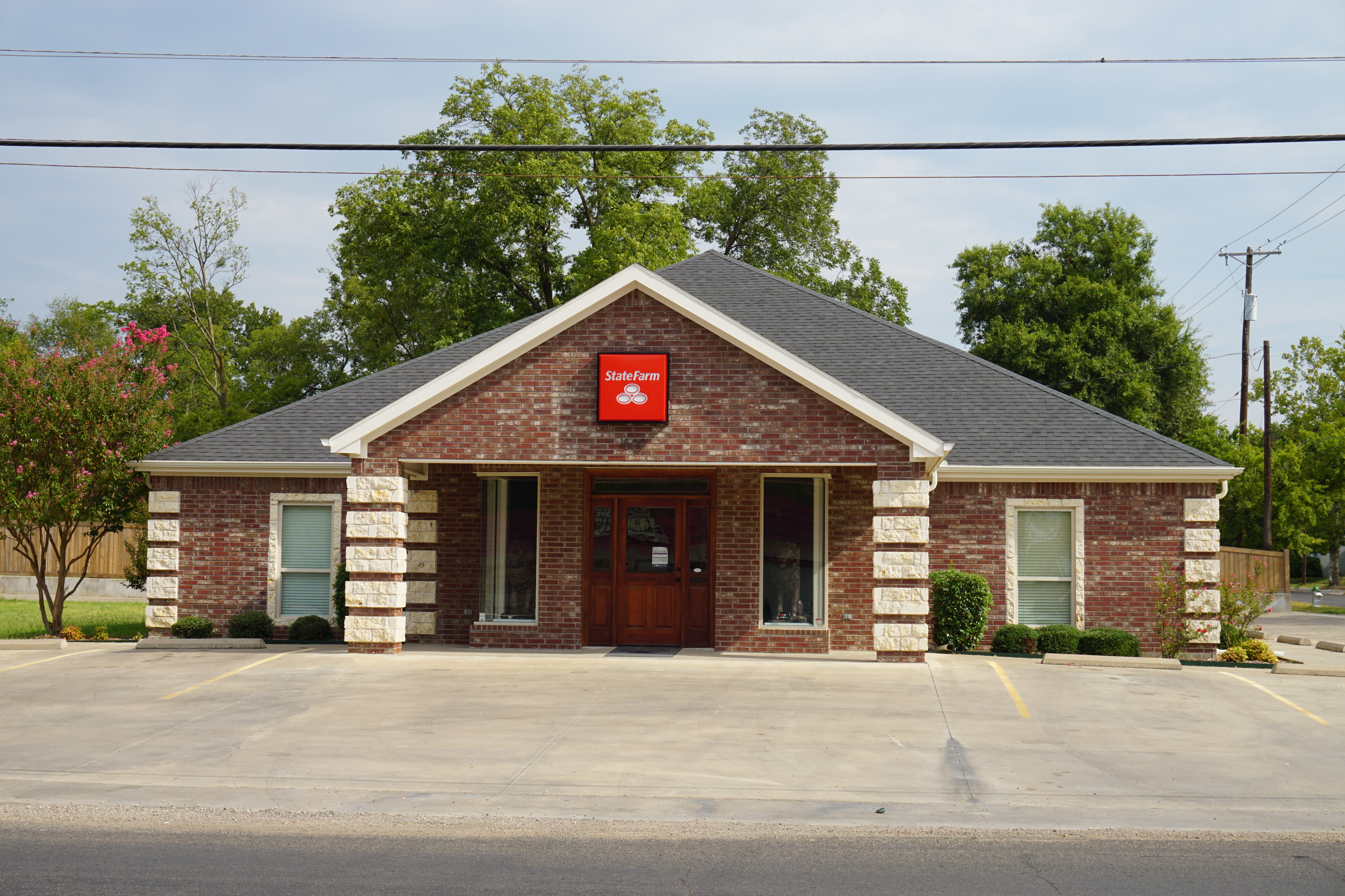 Single-story brick State Farm Insurance office building with red sign above the entrance.