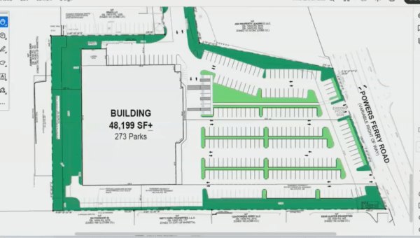 Architectural site plan showing a large building footprint surrounded by parking spaces and green landscaping areas.