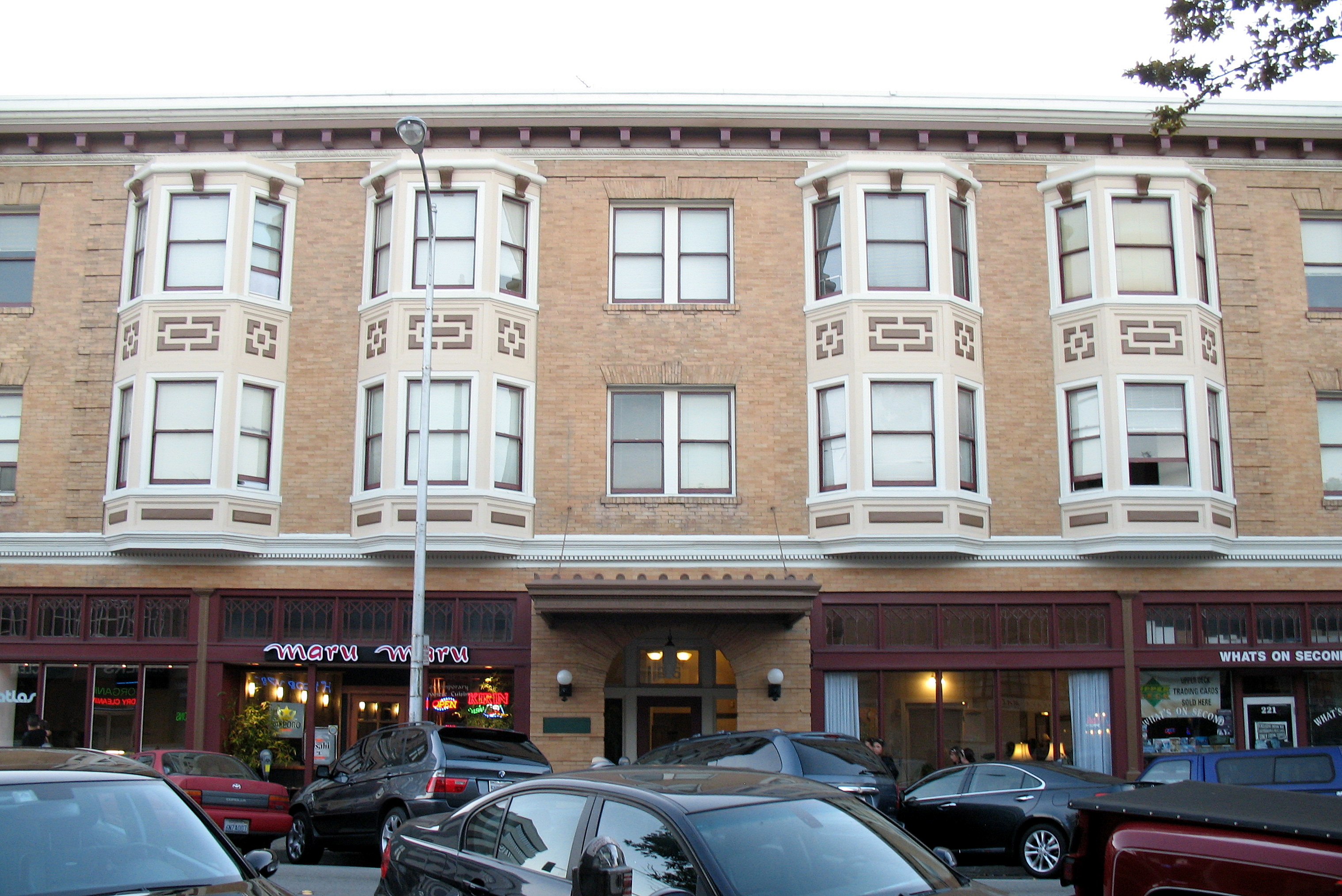 Multi-story brick building with bay windows and decorative facade on a city street.
