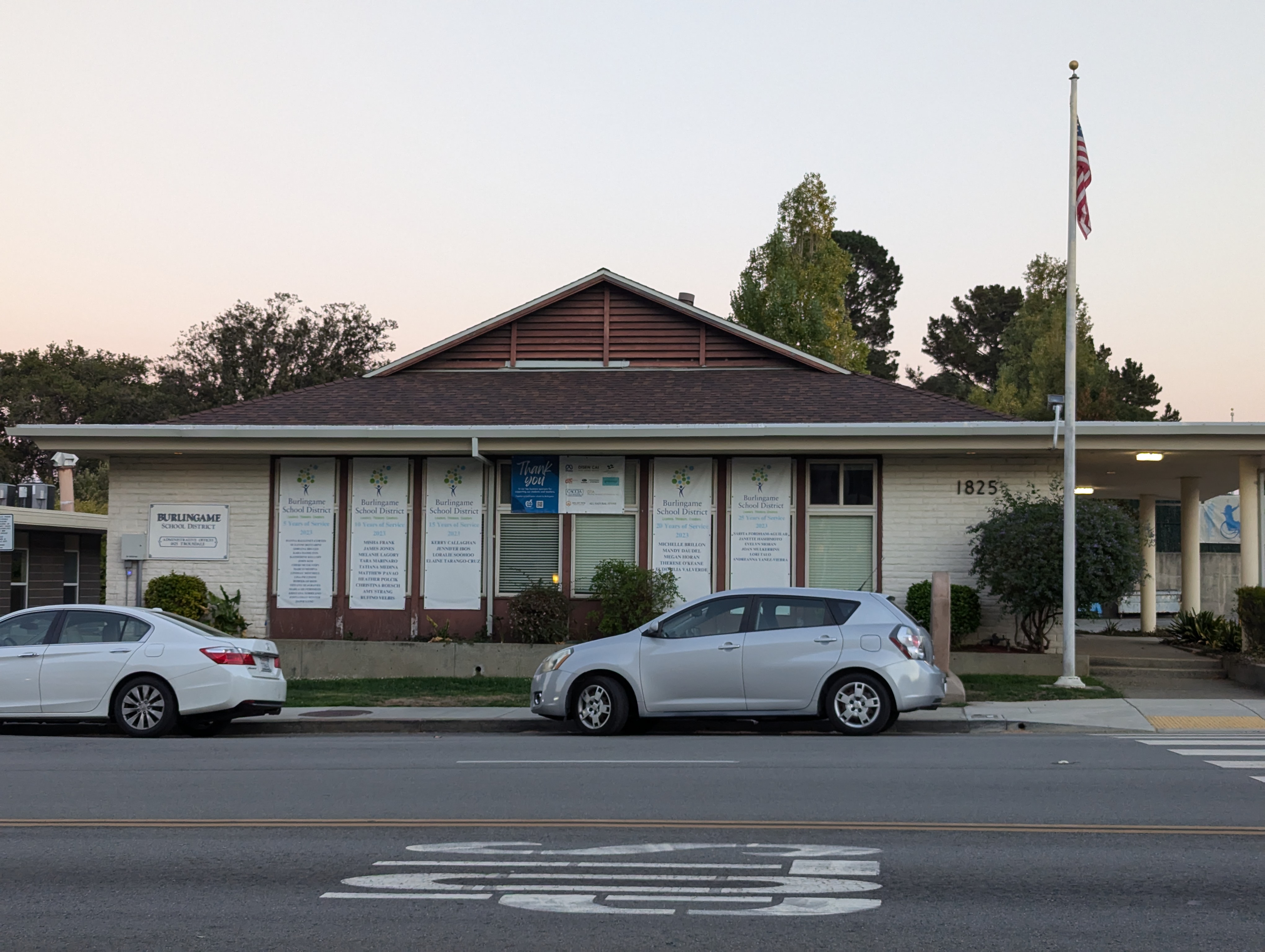 Single-story brick building with an American flag out front at dusk.