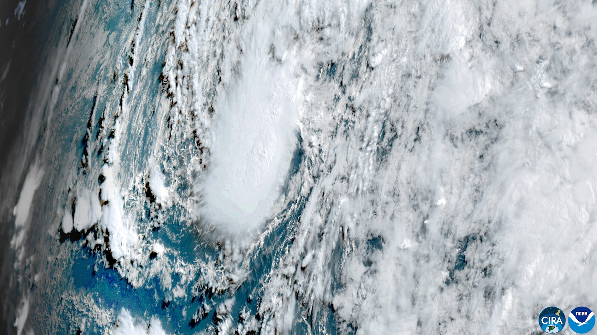 Satellite image of a tropical storm with swirling cloud bands over open ocean.